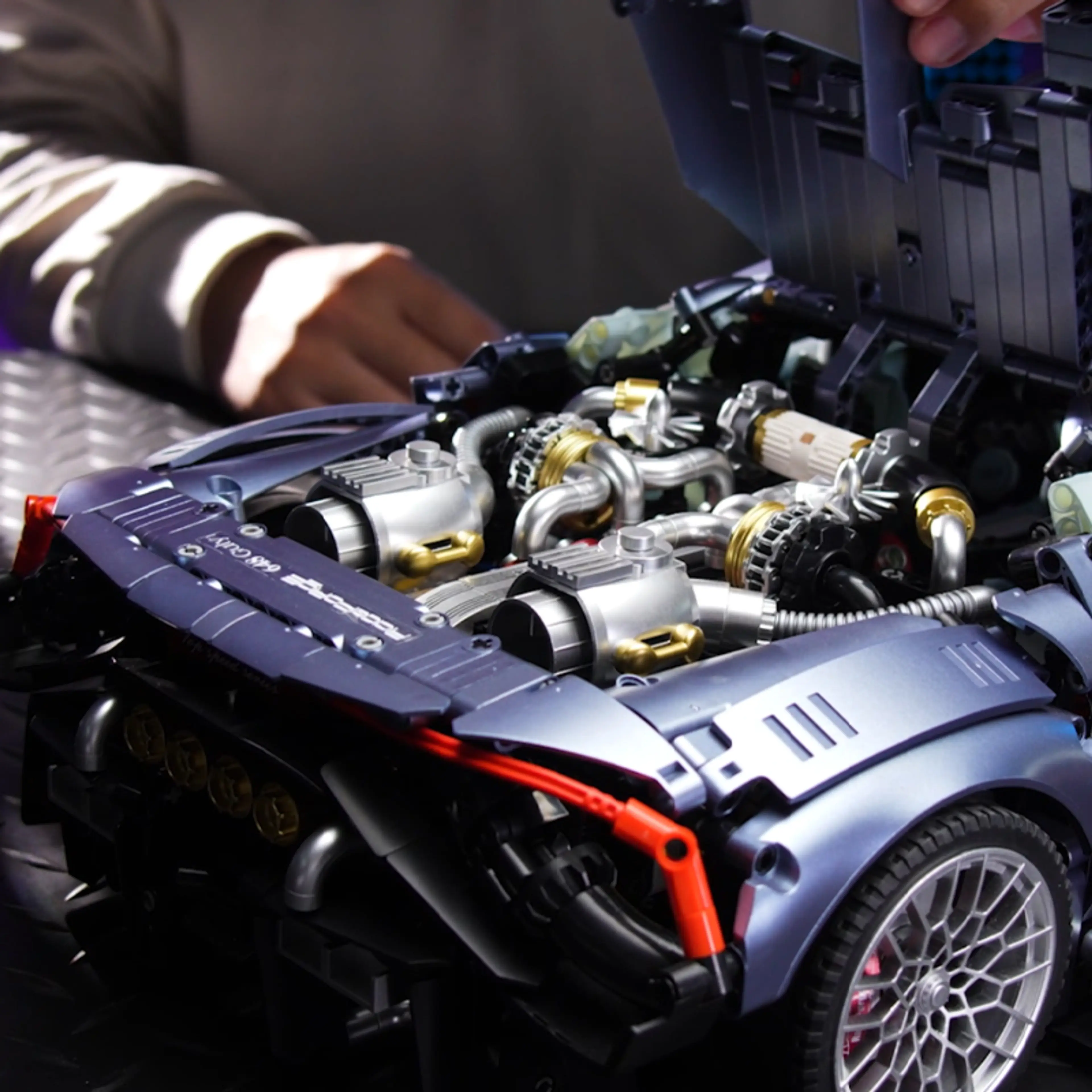 Händer som bygger supersportbilens motorrum med turboaggregat och rörsystem