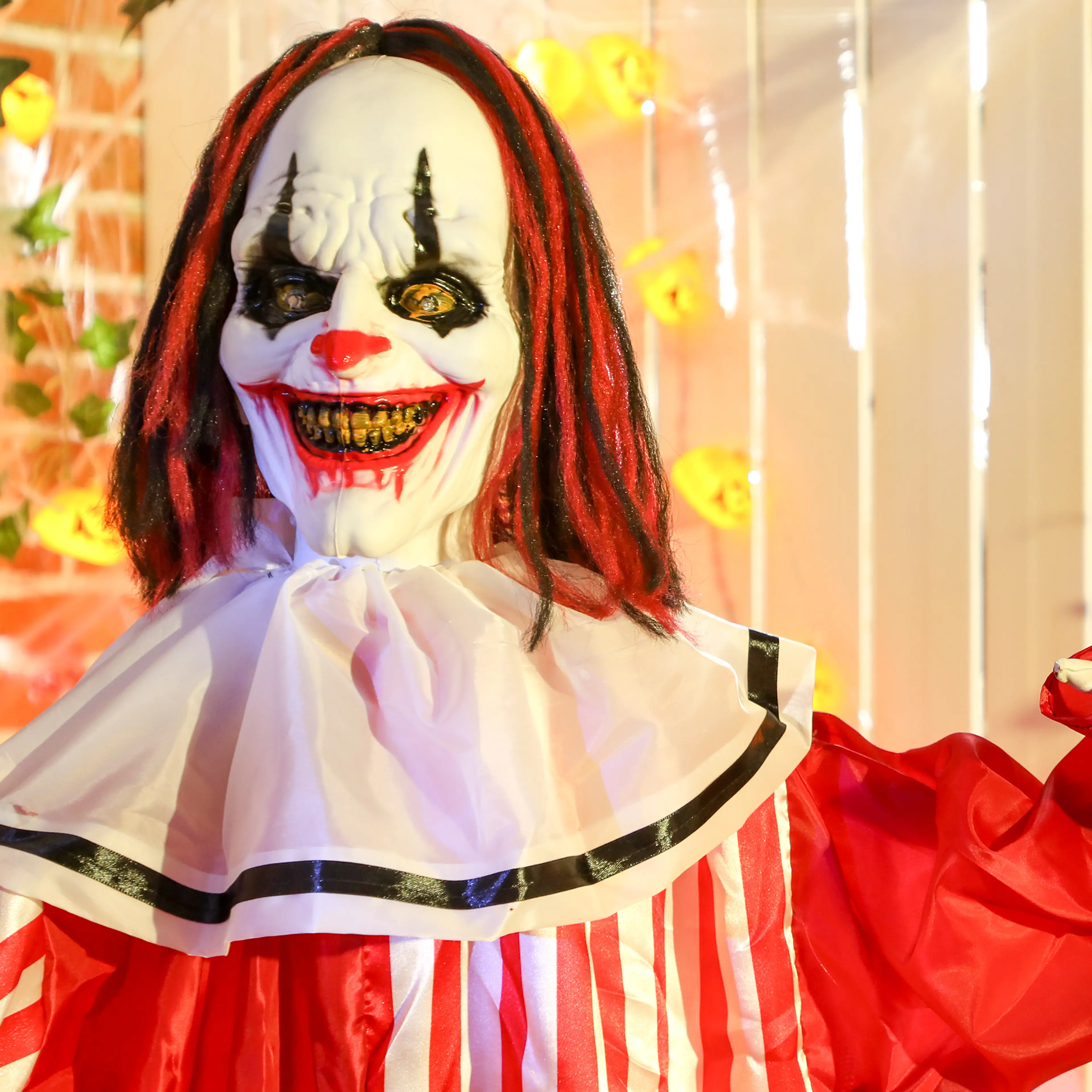 Närbild på clownens grinande ansikte, röda hår och vita krage