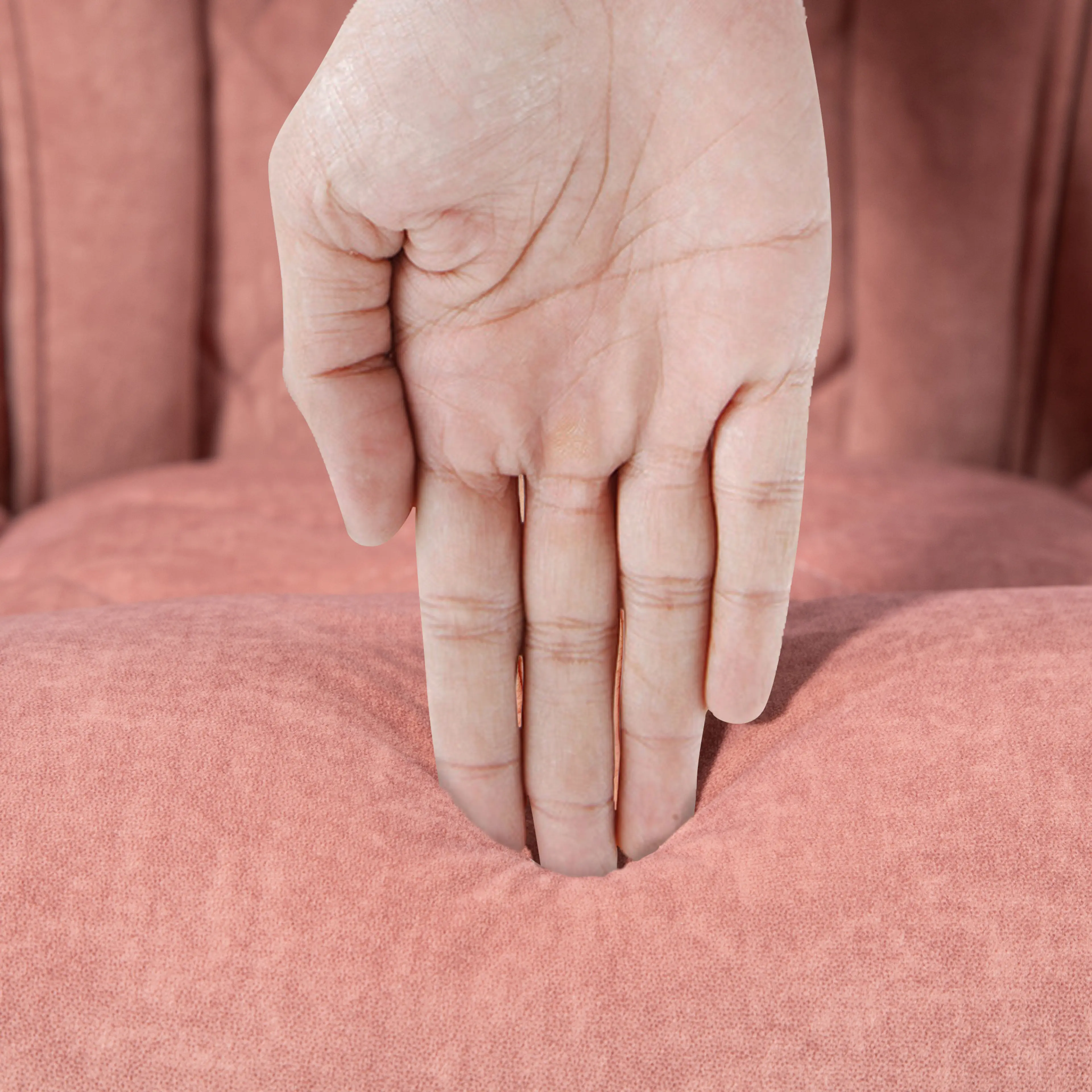 Närbild där en hand trycker ner i den rosa sammetsytan
