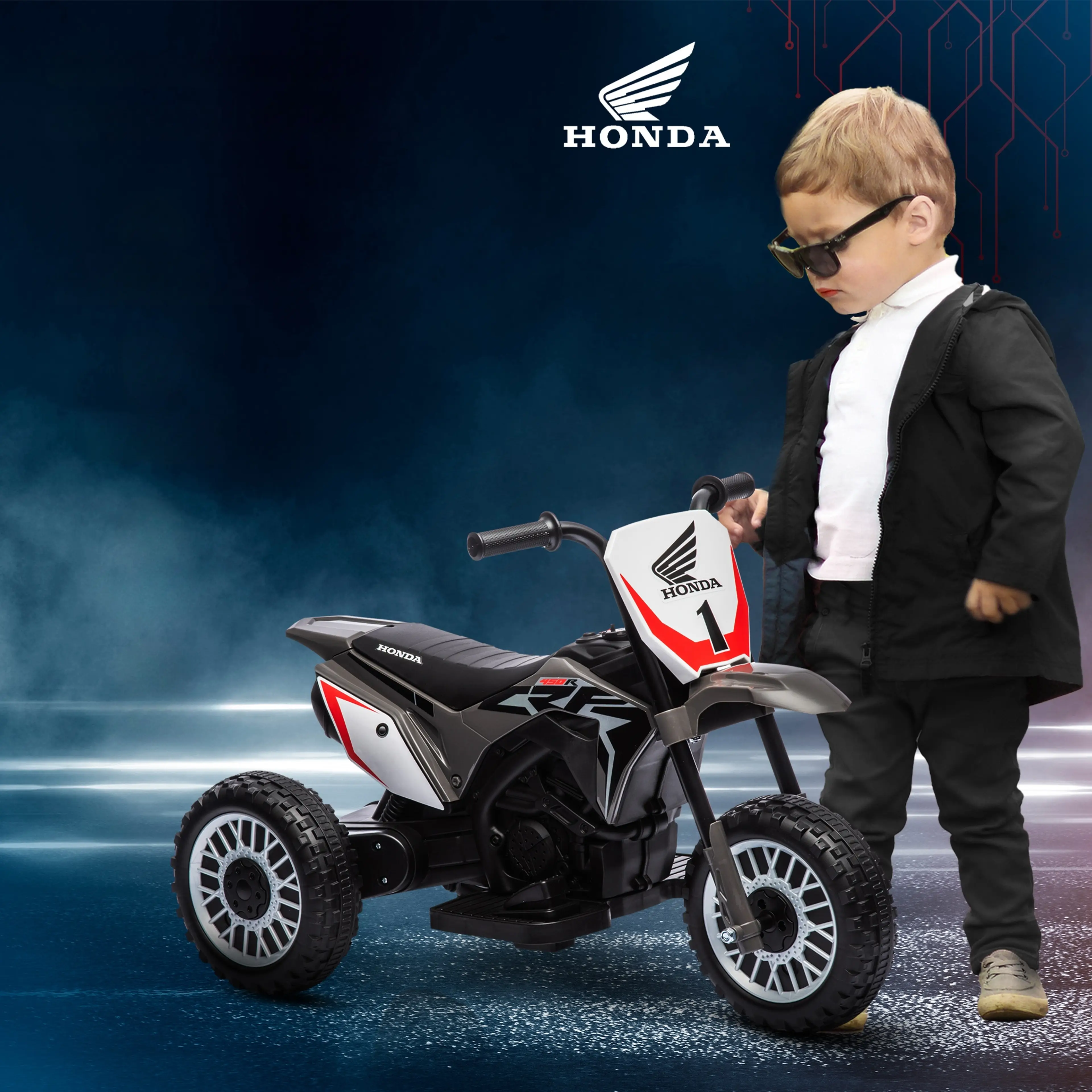 Barn i solglasögon står bredvid den trehjuliga Honda-elcrossen i grått och svart mot mörkblå bakgrund.