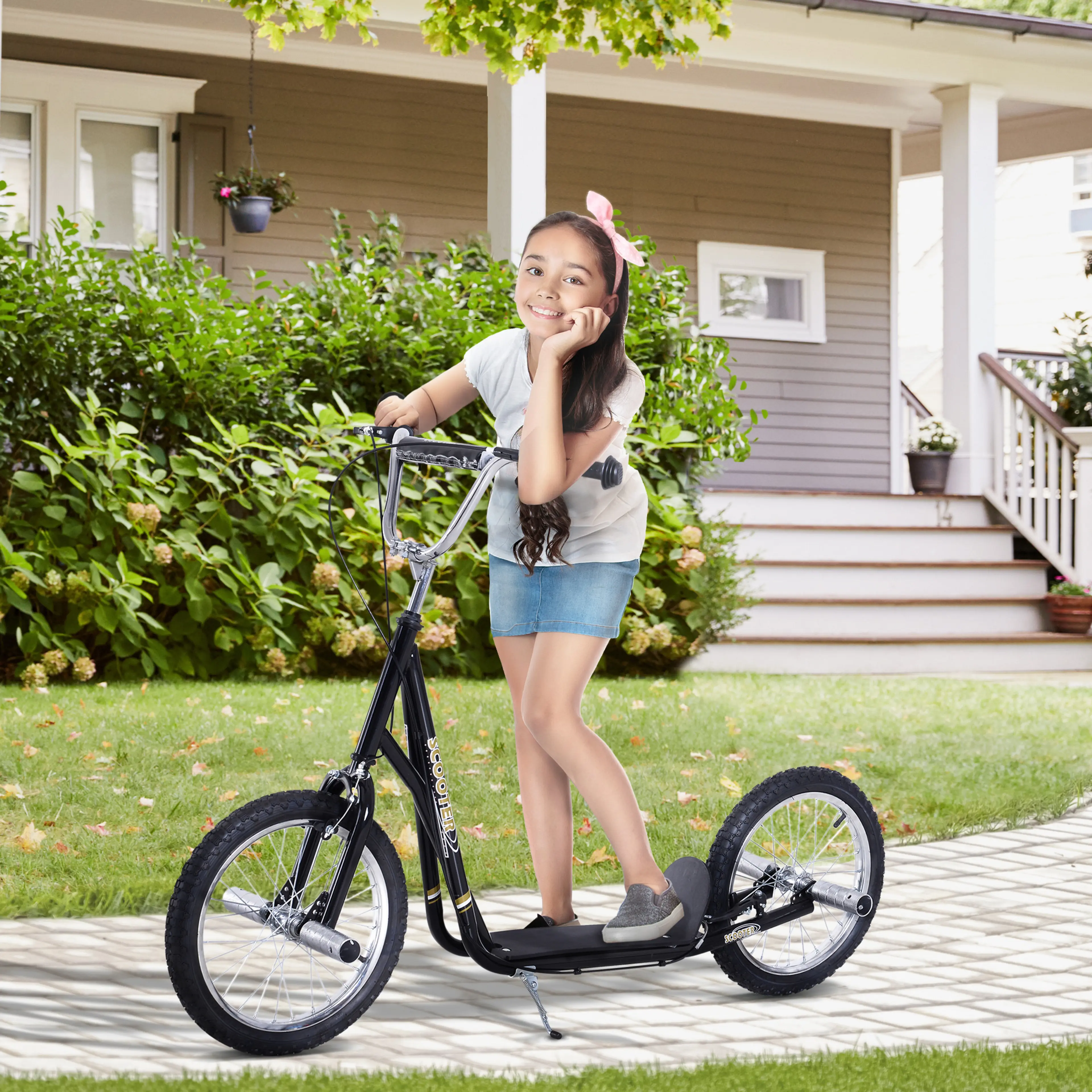 Flicka åker svart sparkcykel på en uppfart framför ett hus