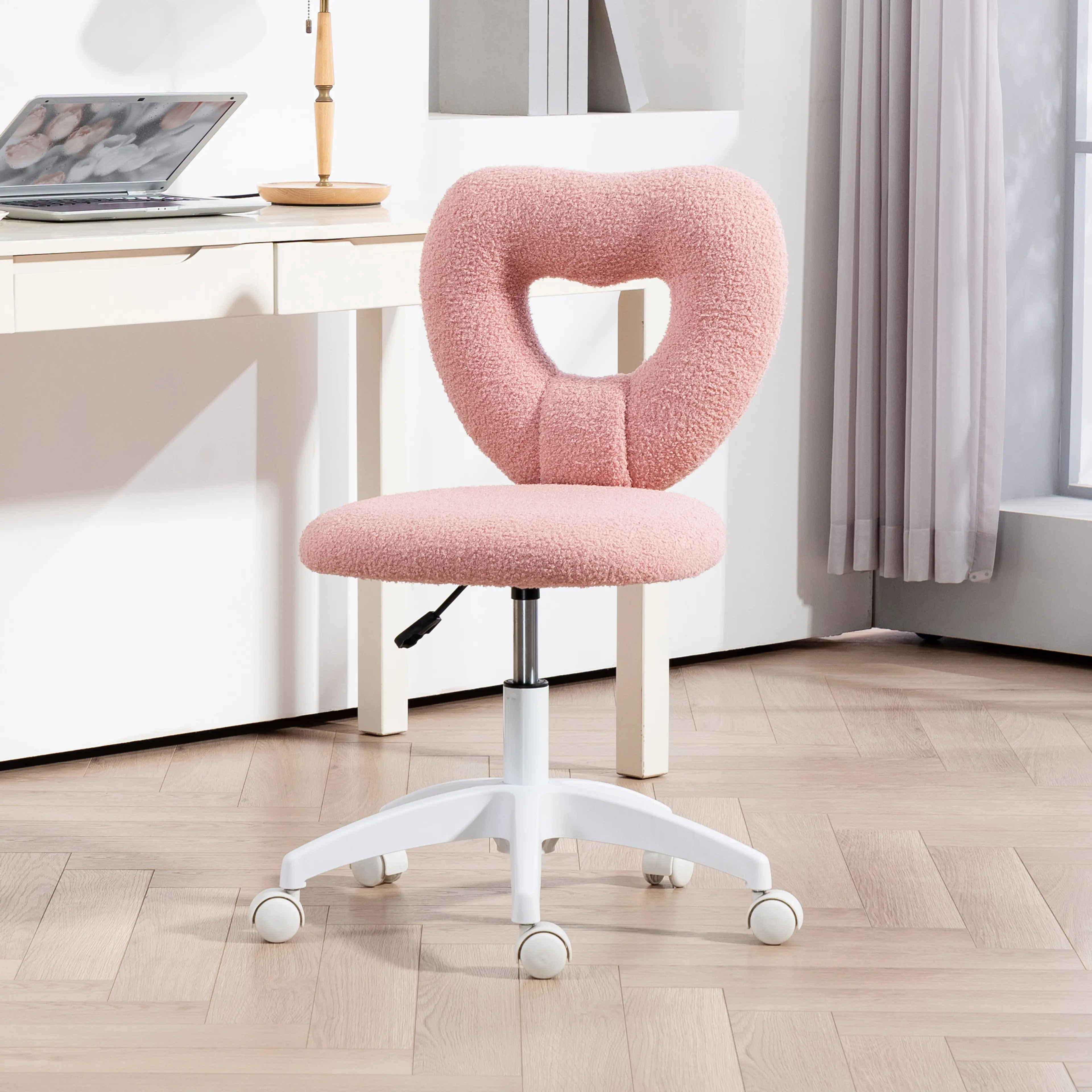 Skrivbordsstol i rosa teddytyg med hjärtformad rygg, vid ett bord i ett ljust rum