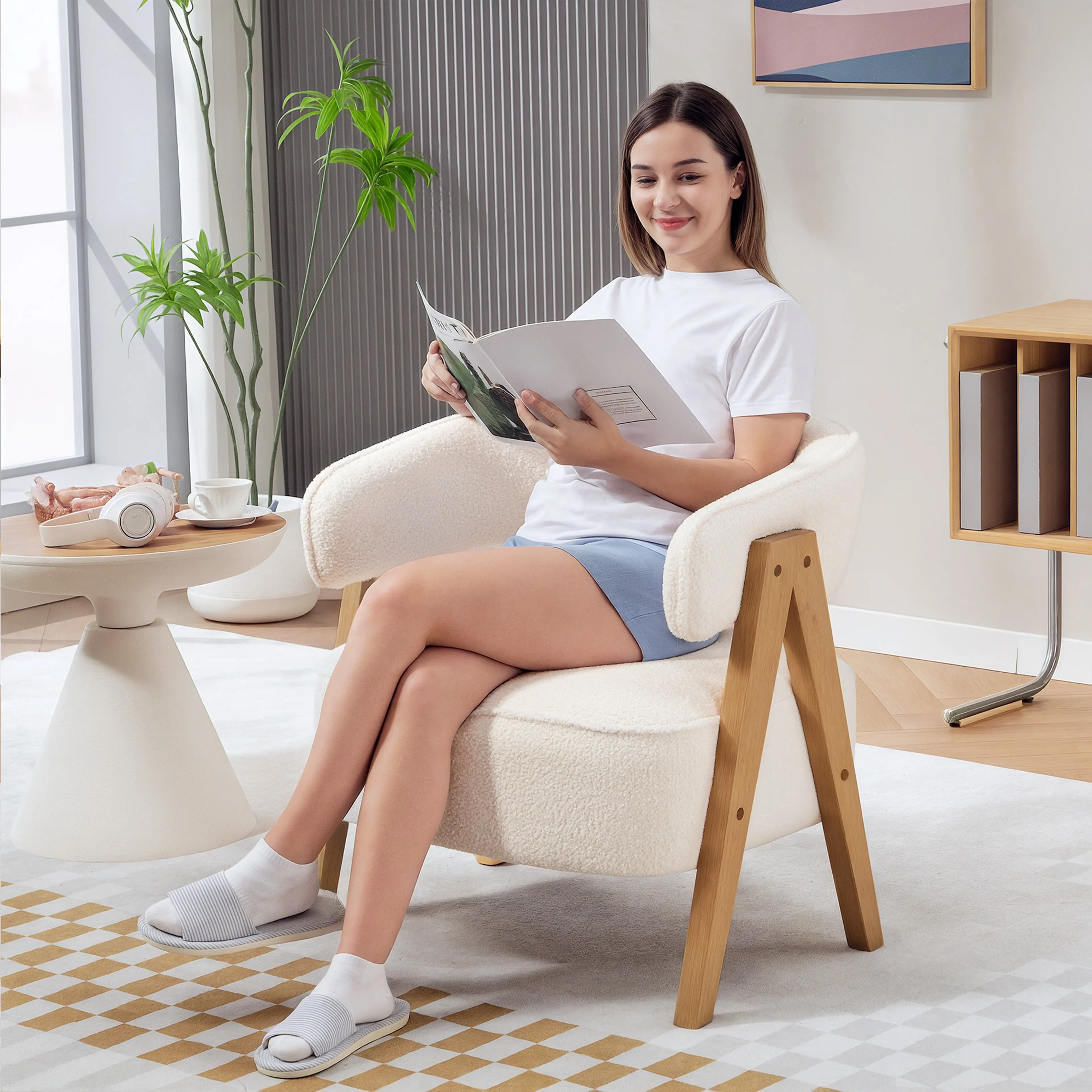 Den vita fåtöljen i teddyfleece i ett ljust vardagsrum med krukväxt och sidobord