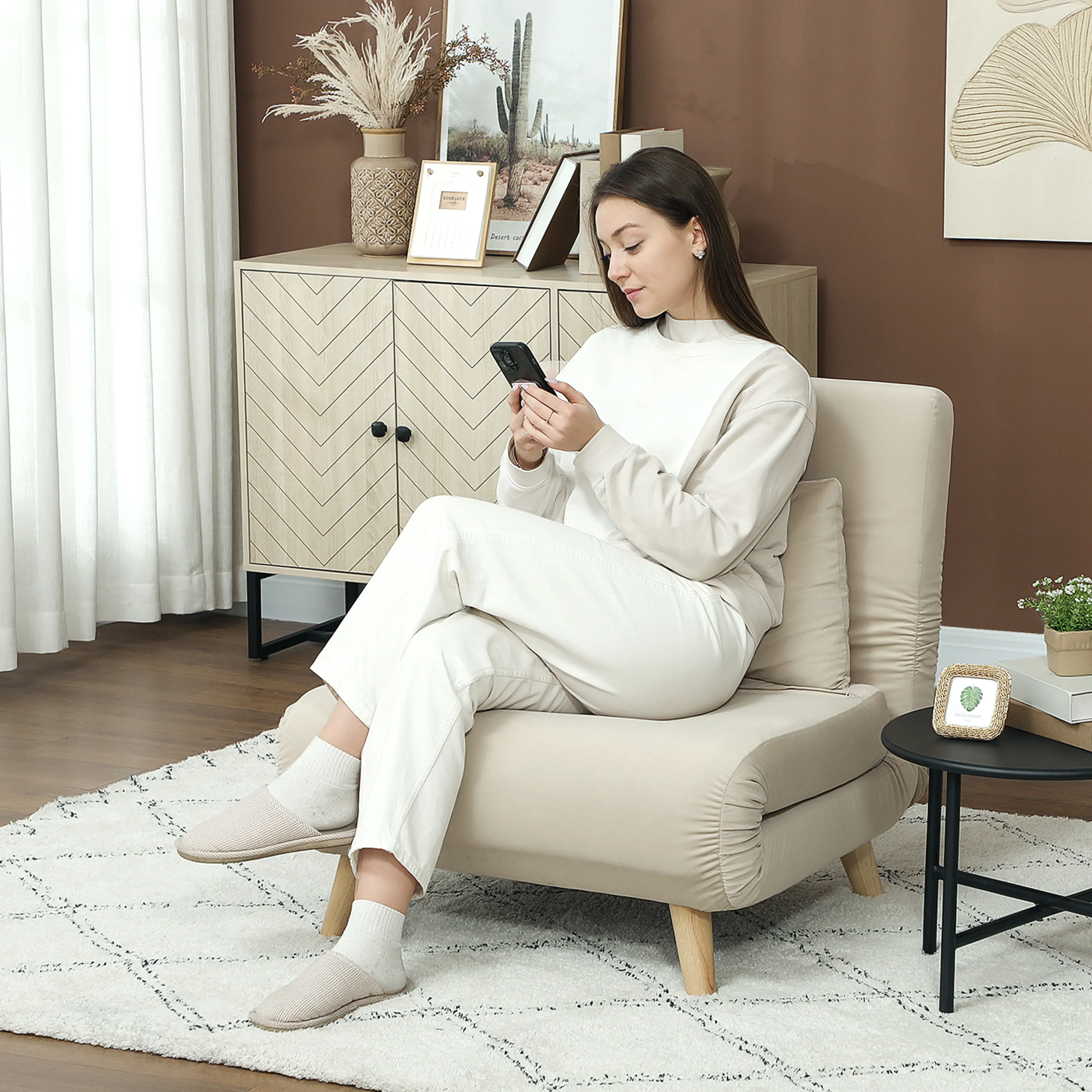 En person sitter i den beige bäddfåtöljen i ett vardagsrum