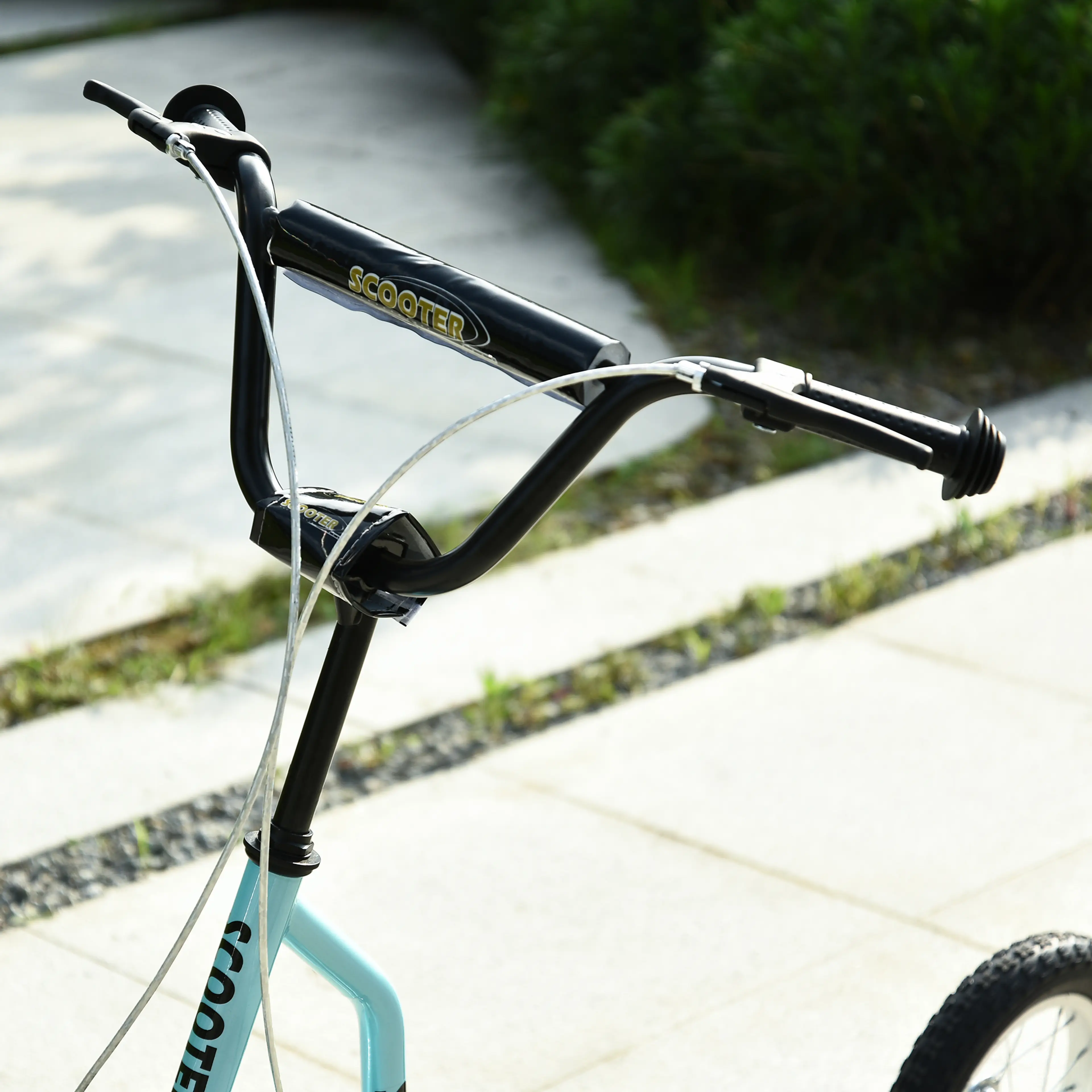 Närbild på det svarta styret på turkos sparkcykel
