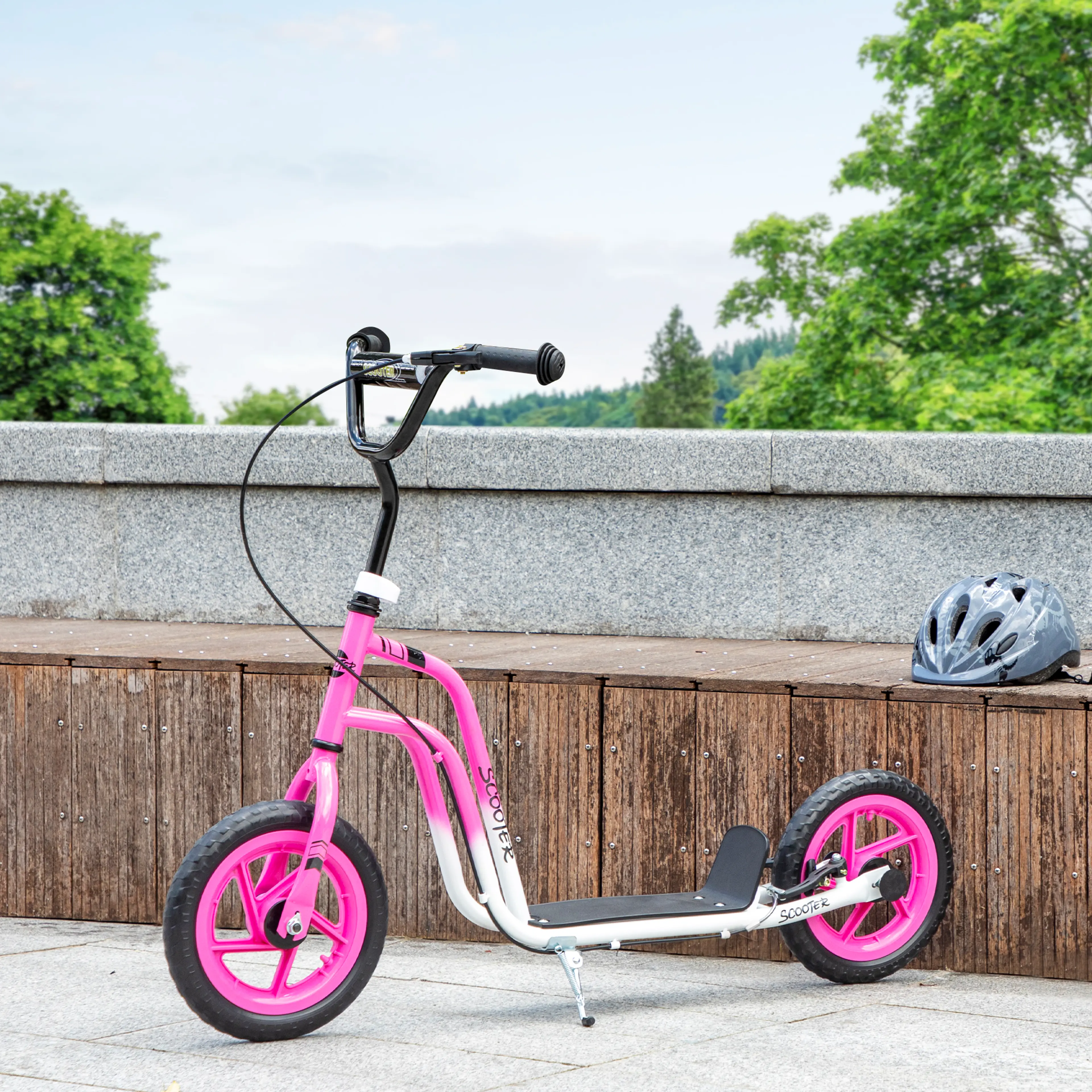 Den rosa sparkcykeln lutad mot en trävägg med hjälmen bredvid
