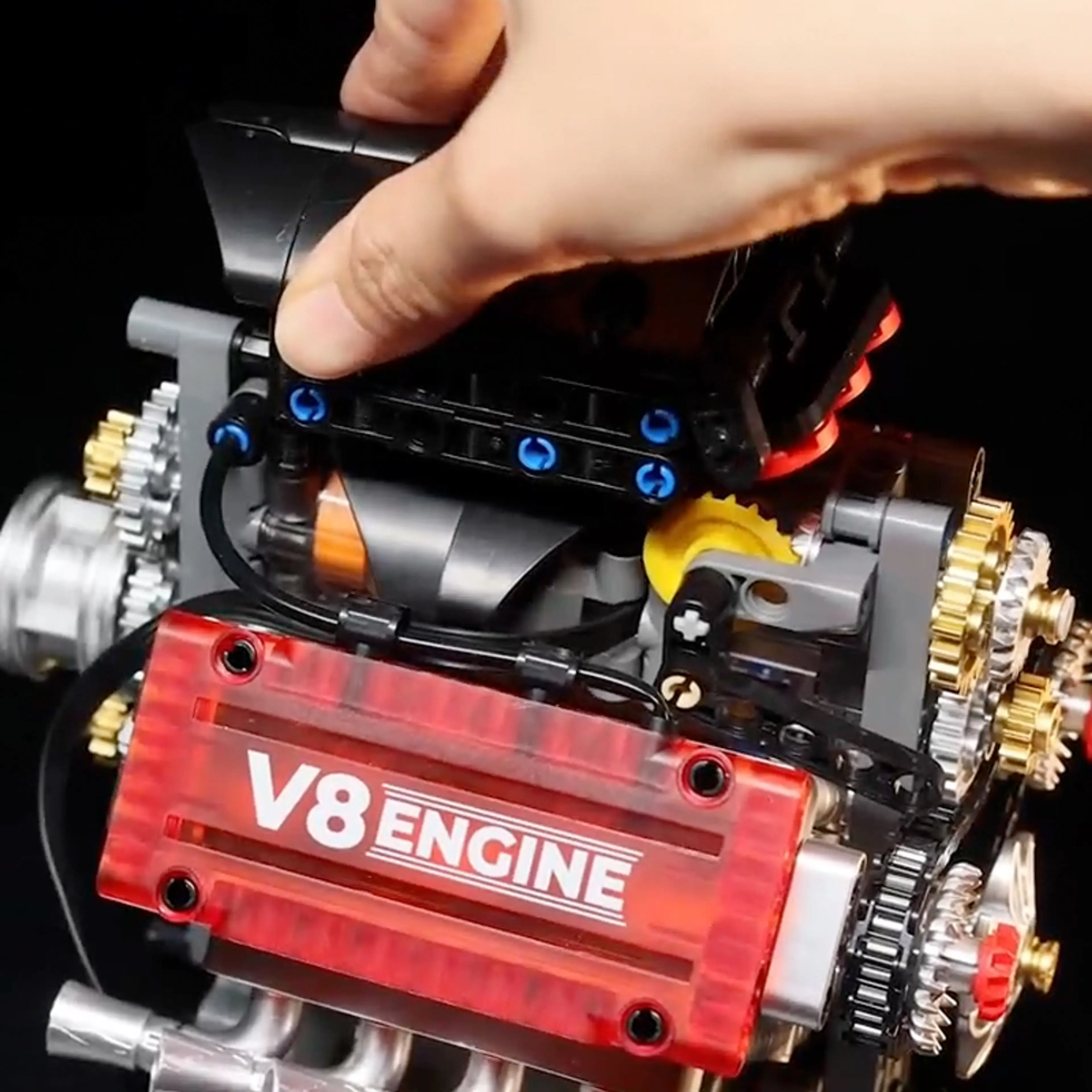 Hand som håller den färdigbyggda V8-motorn i klossar – visar modellens storlek