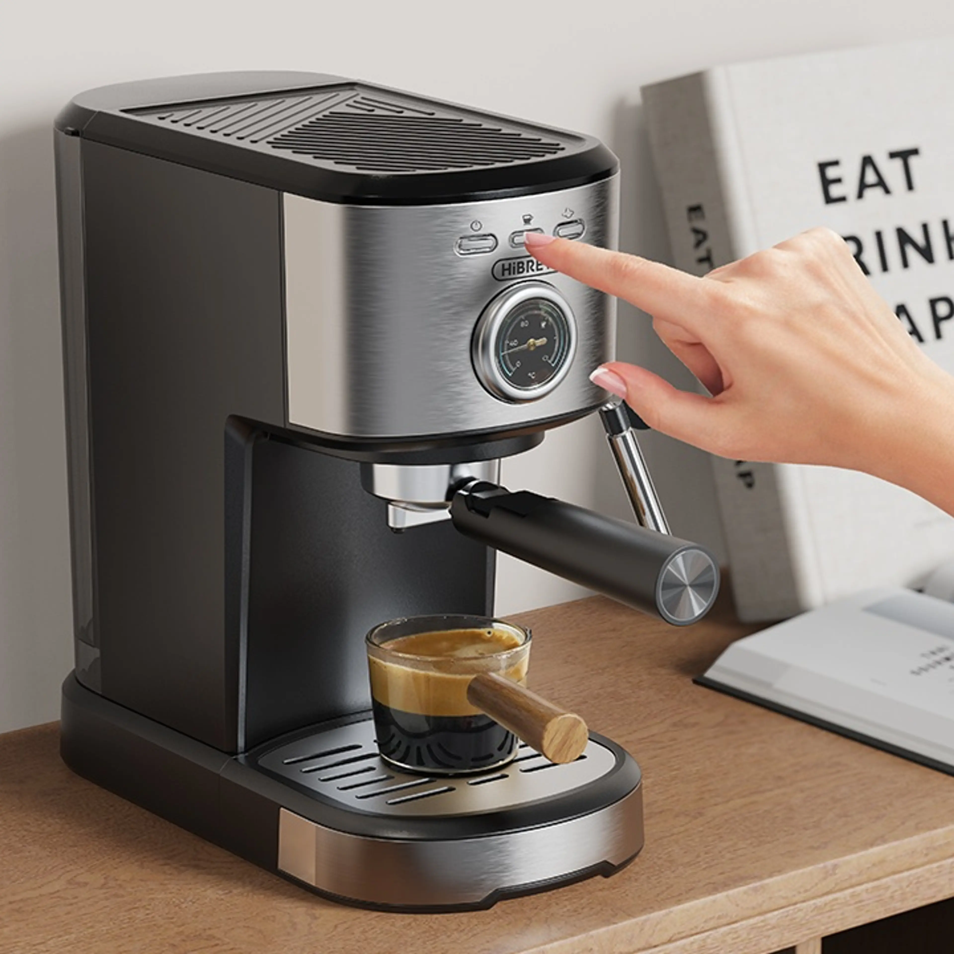 Espressomaskinen på ett skrivbord medan en hand trycker på kaffeknappen och shotten rinner ner i koppen
