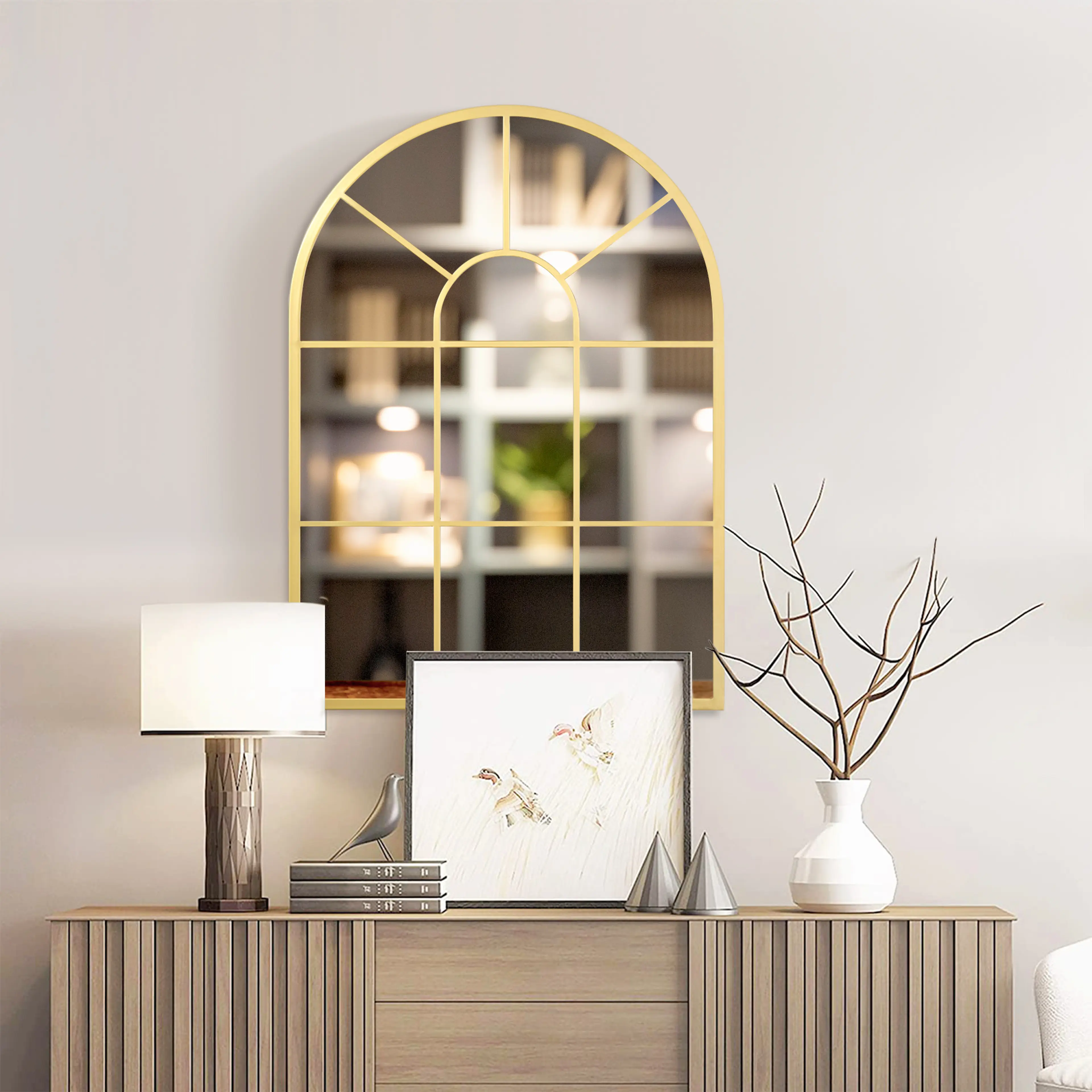 Fönsterspegeln i guld hänger över en sideboard med lampa, tavla och vas