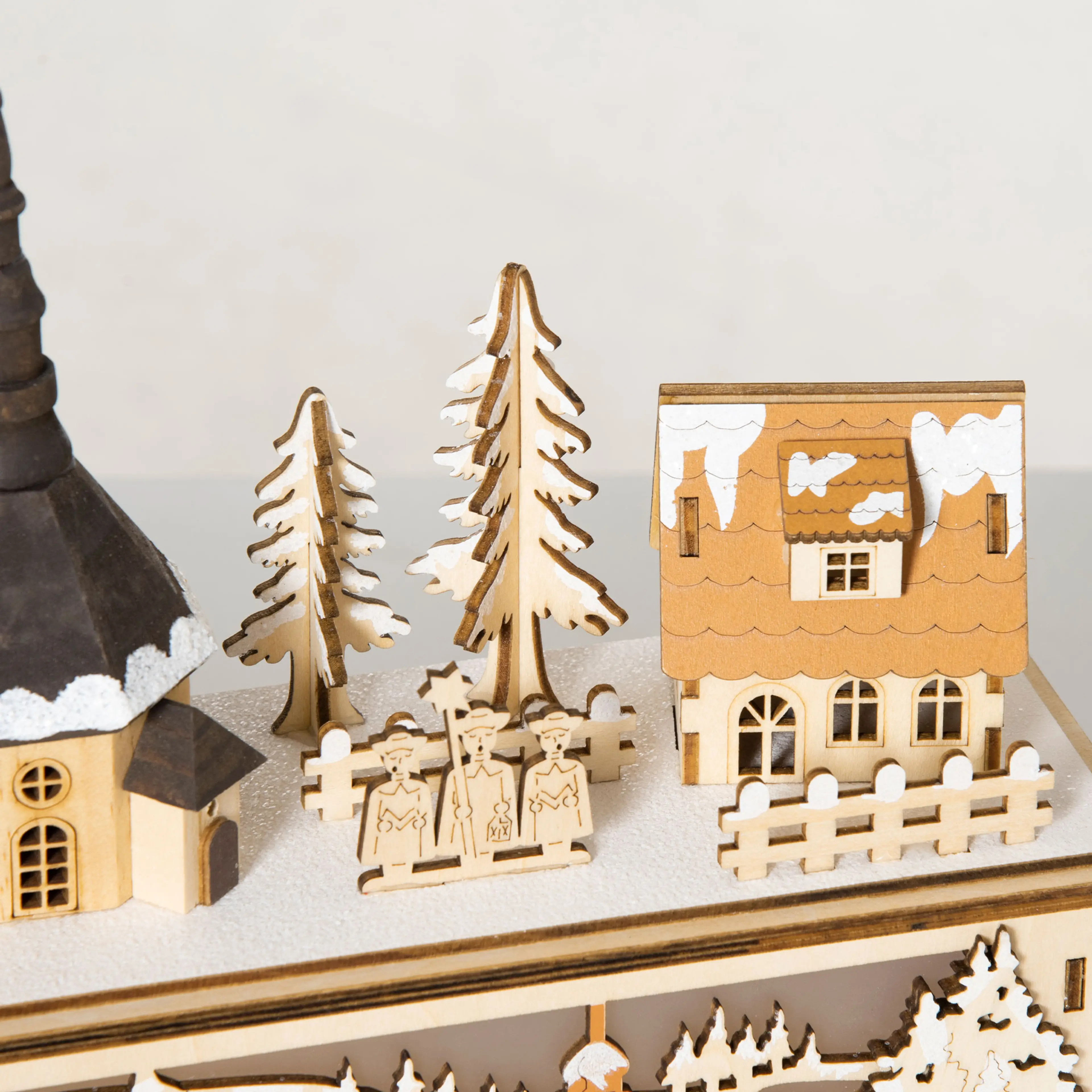 Närbild på ett snötäckt hus, granar och ett staket i julbyn