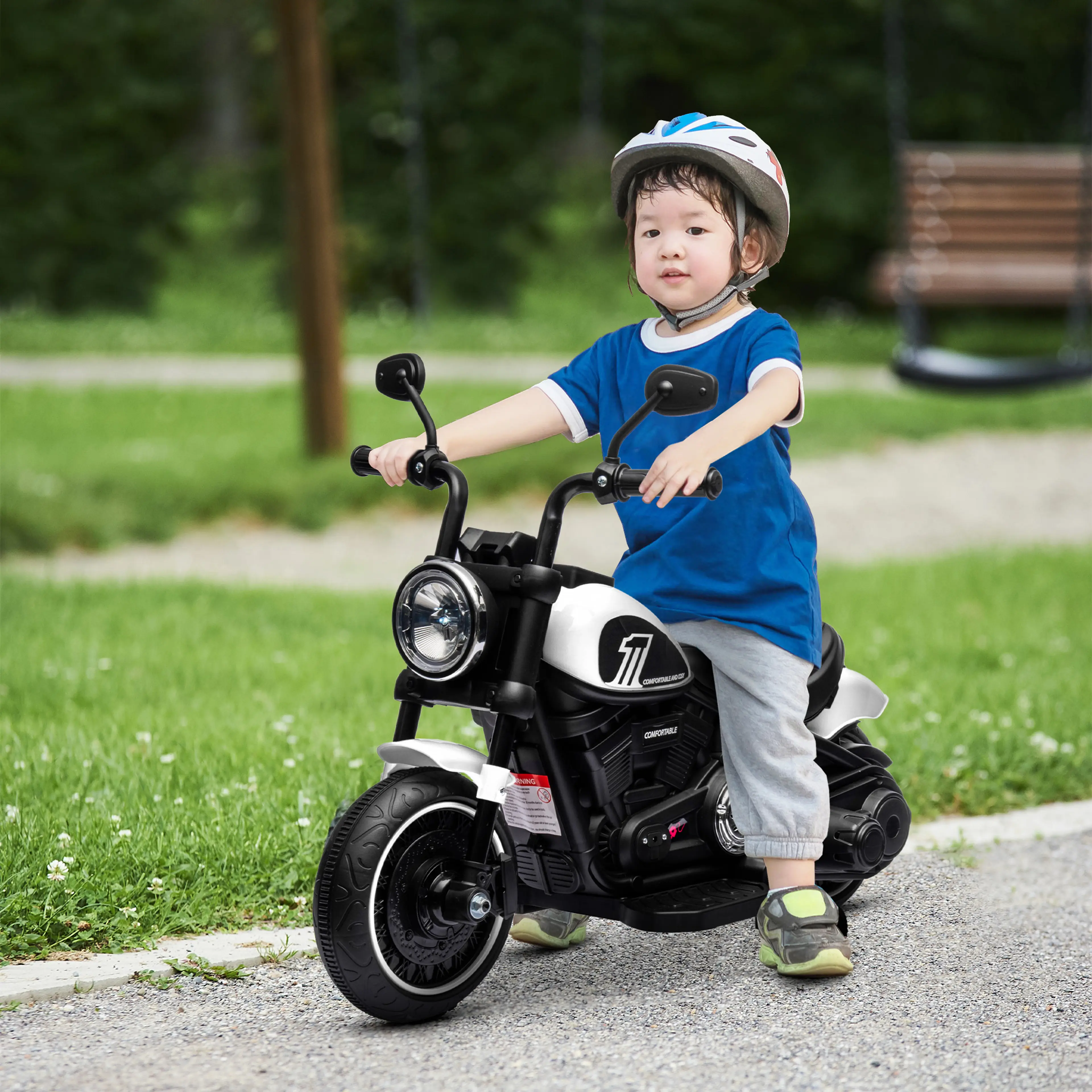 Barn med cykelhjälm kör den vita elmotorcykeln på en gångväg i en park