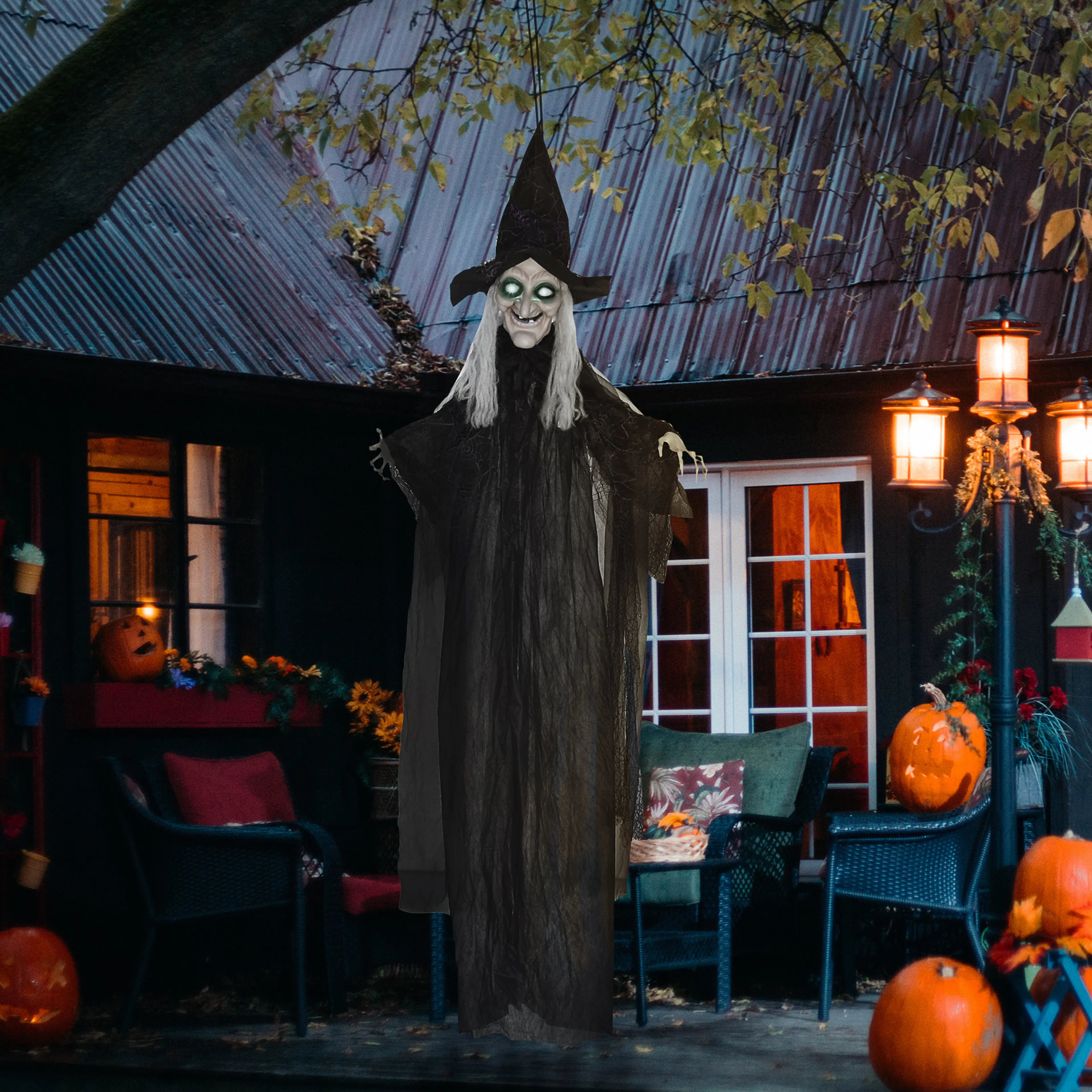Häxan på en veranda med pumpor och tända lyktor