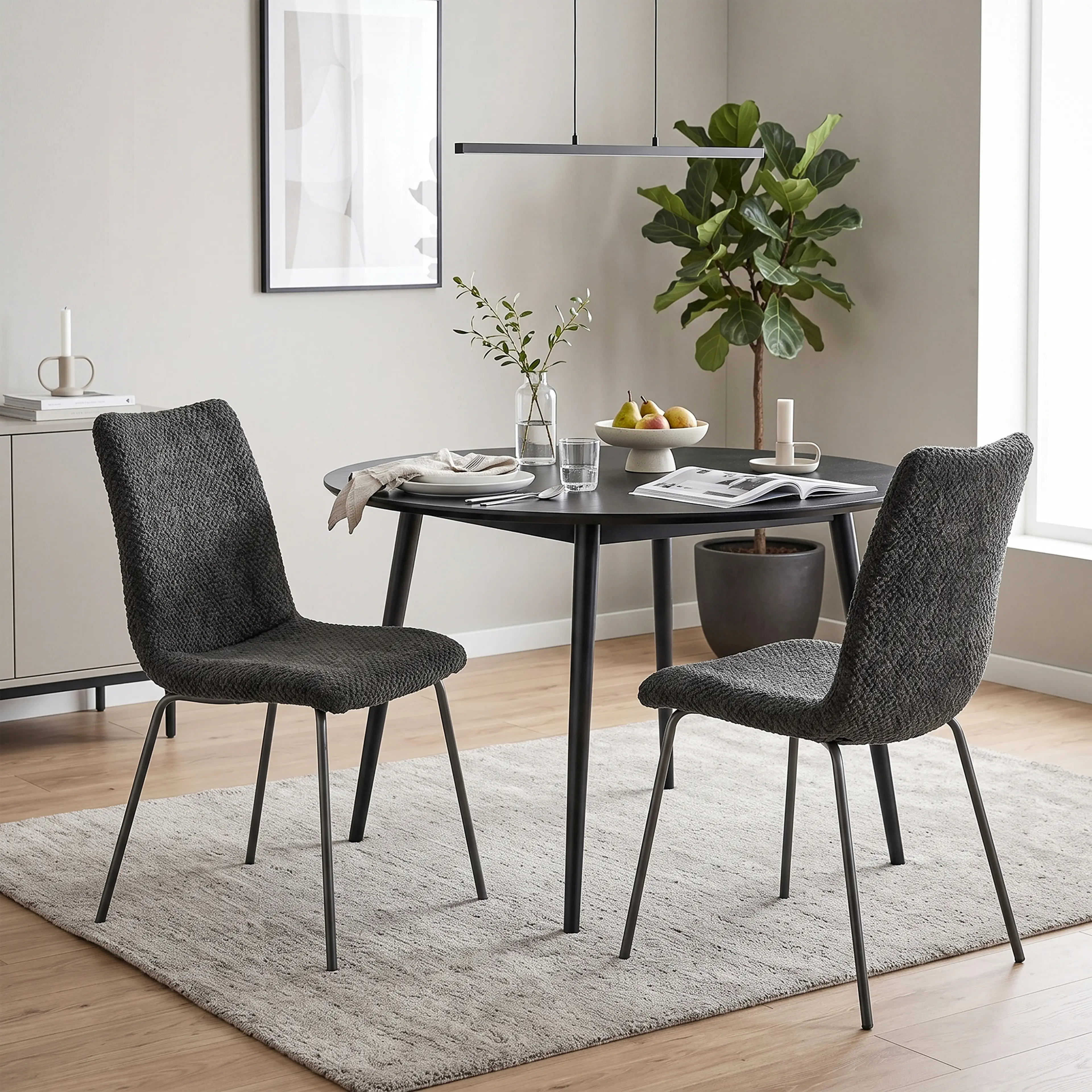 Matstolarna vid ett runt, svart matbord med fruktskål och en tidning