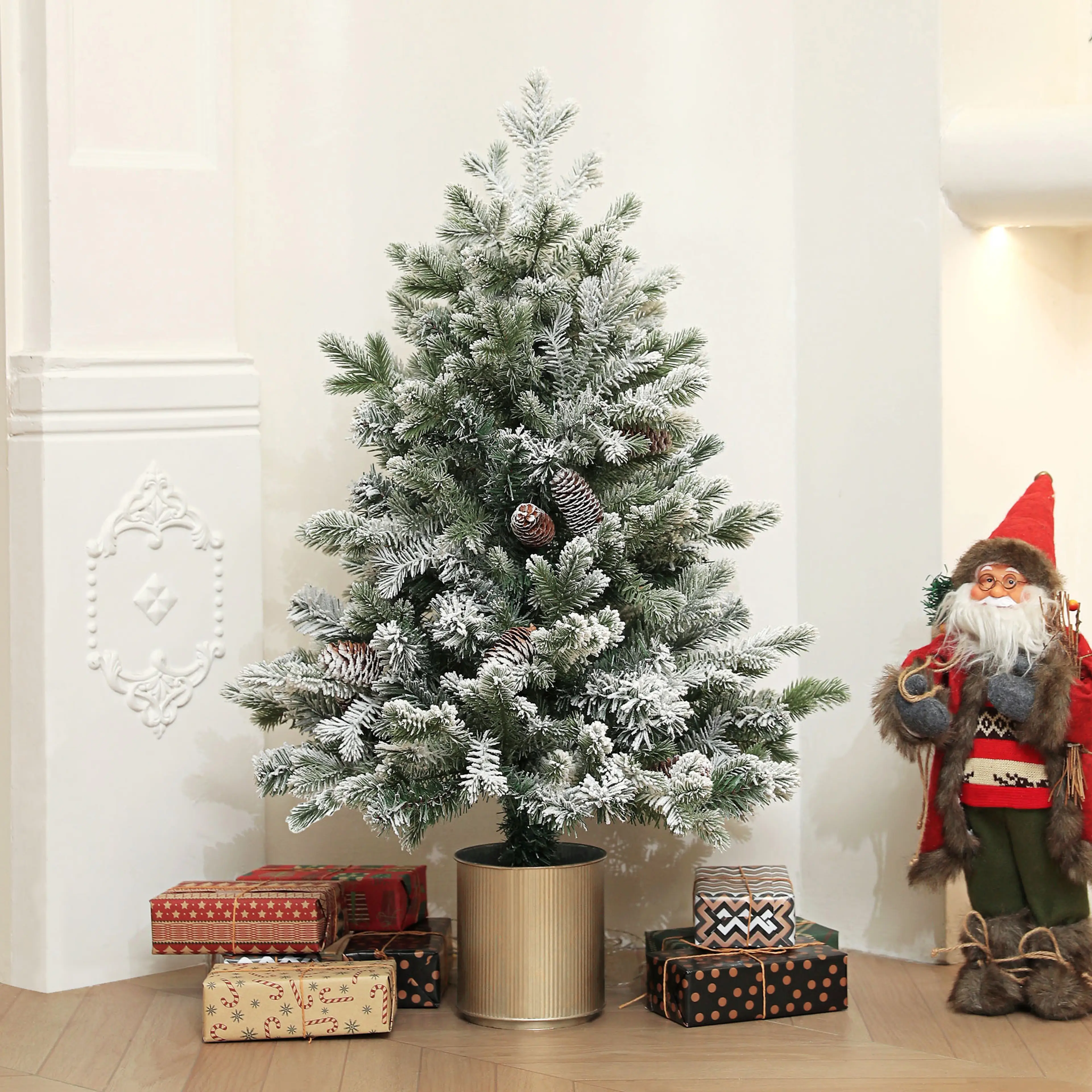 Julgranen bredvid en tomtefigur och julklappar i ett ljust rum