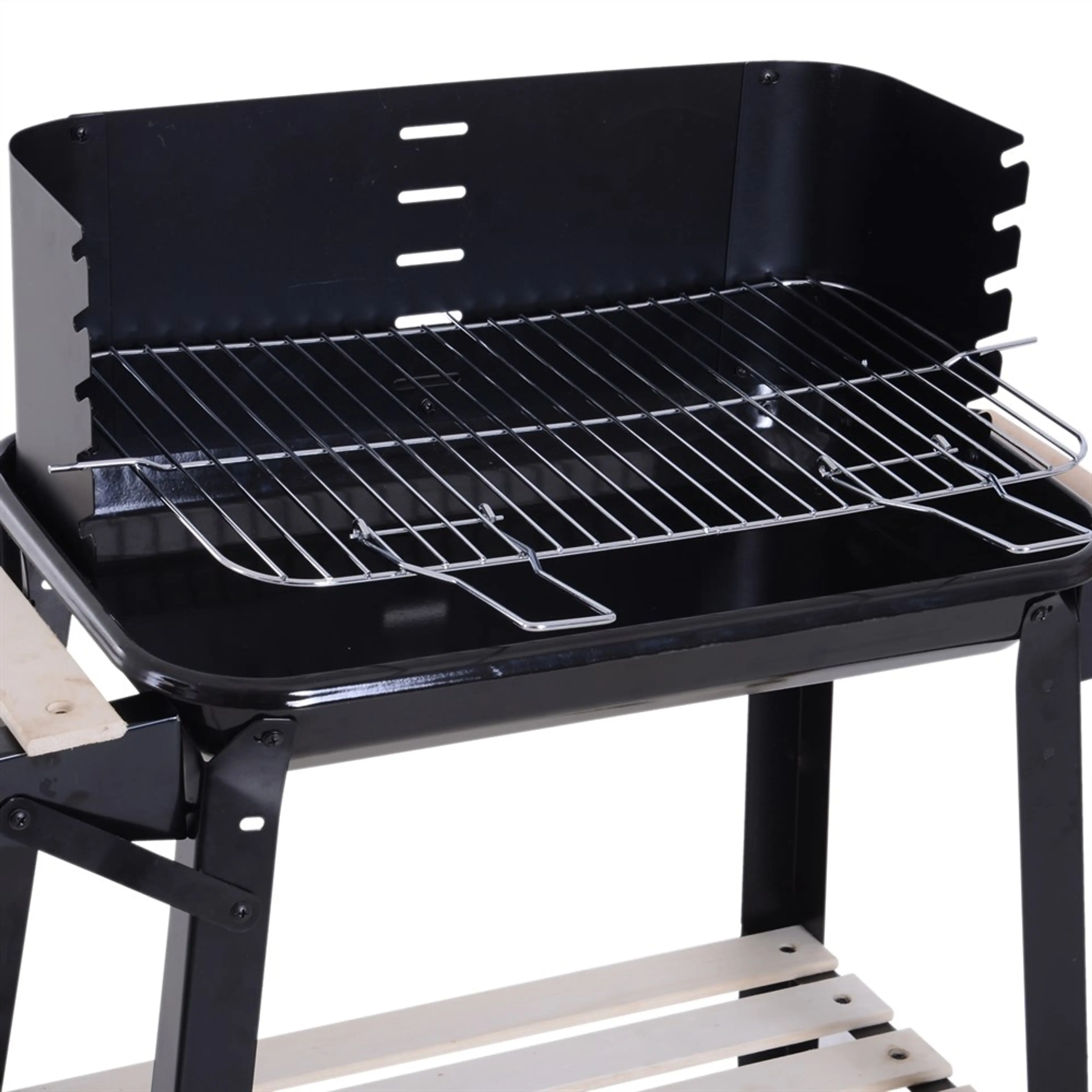 Förkromat grillgaller över kolbädden med vindskydd bakom