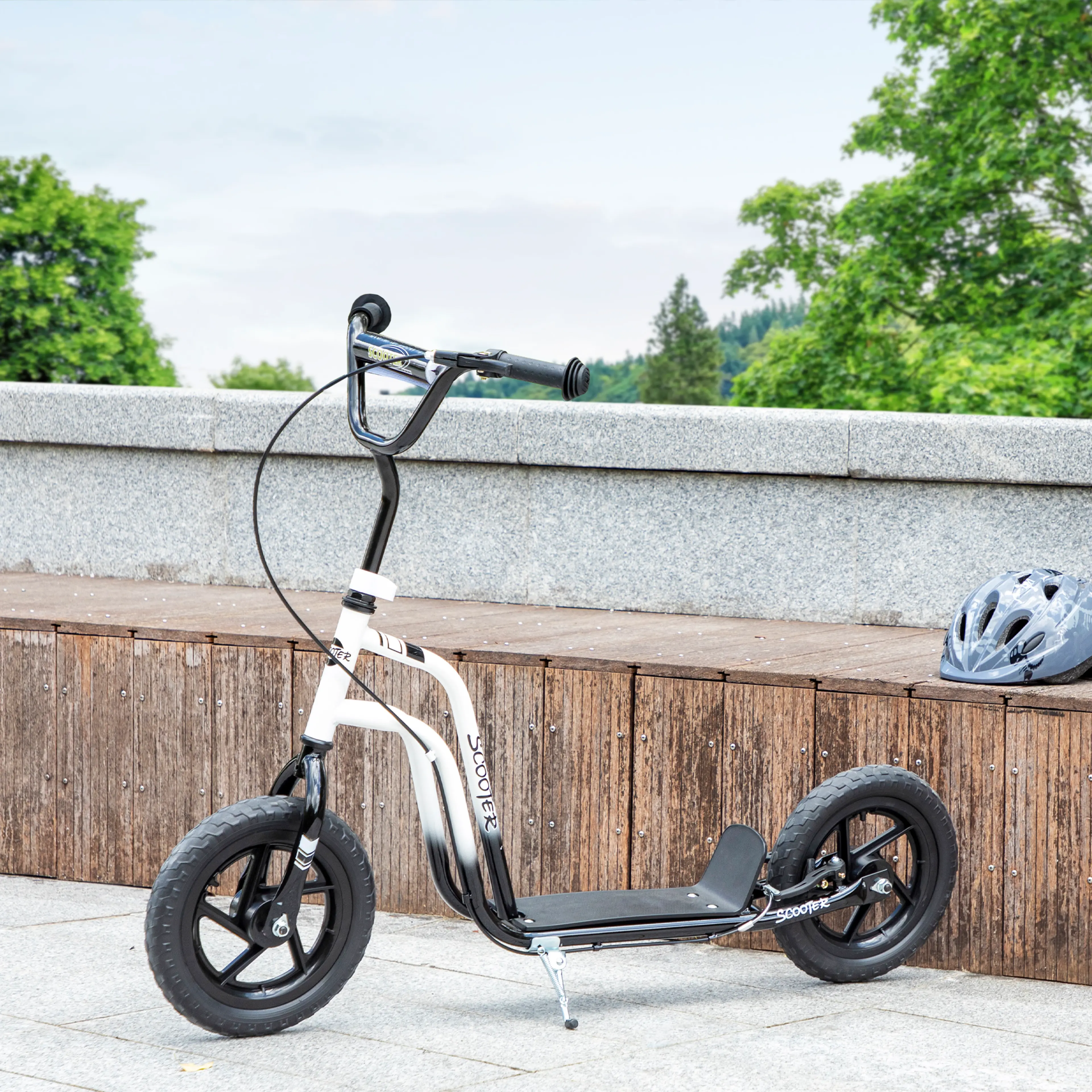 Den vita sparkcykeln uppställd mot en stenmur med hjälmen bredvid