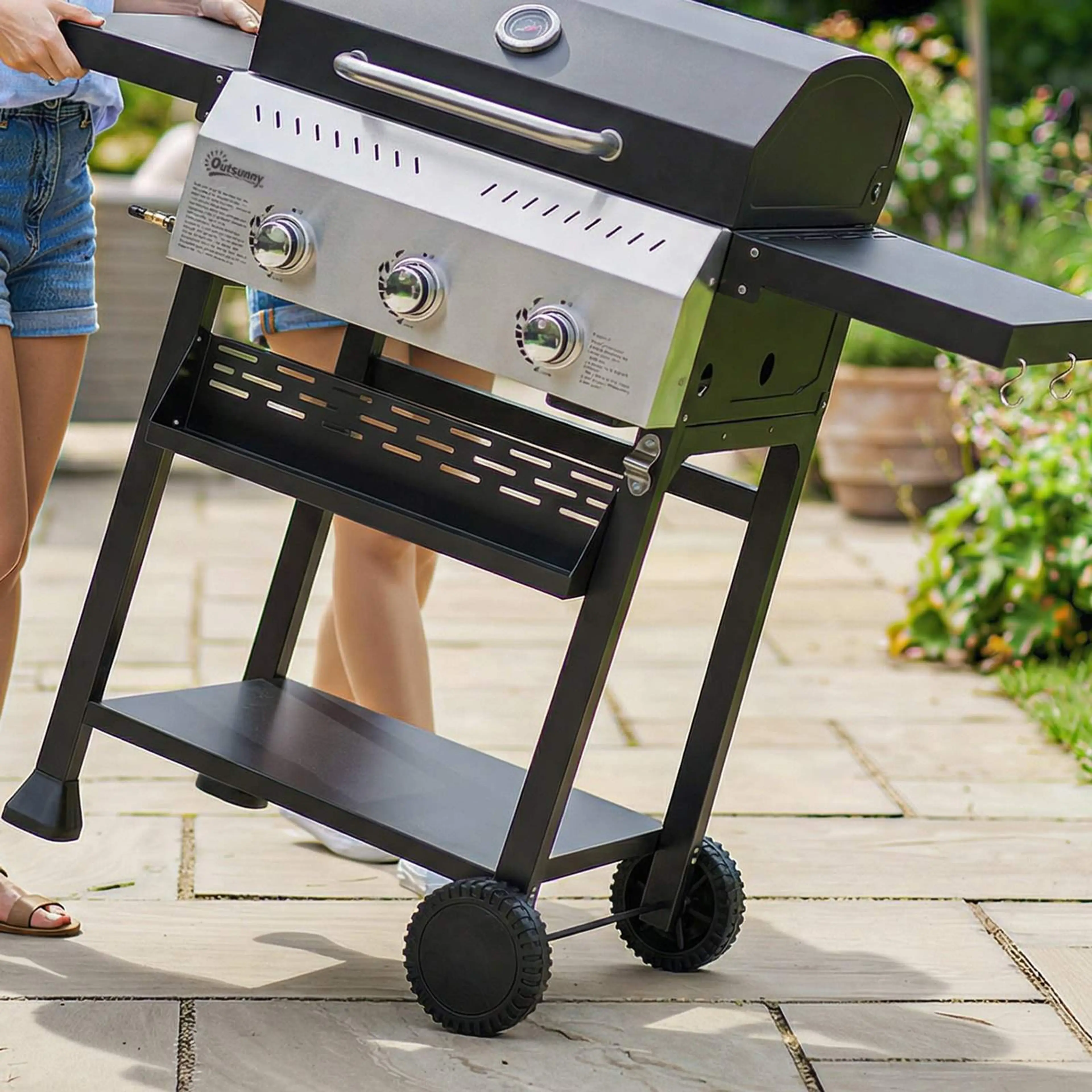 Gasolgrillen rullas på sina två hjul med det ena sidobordet nedfällt