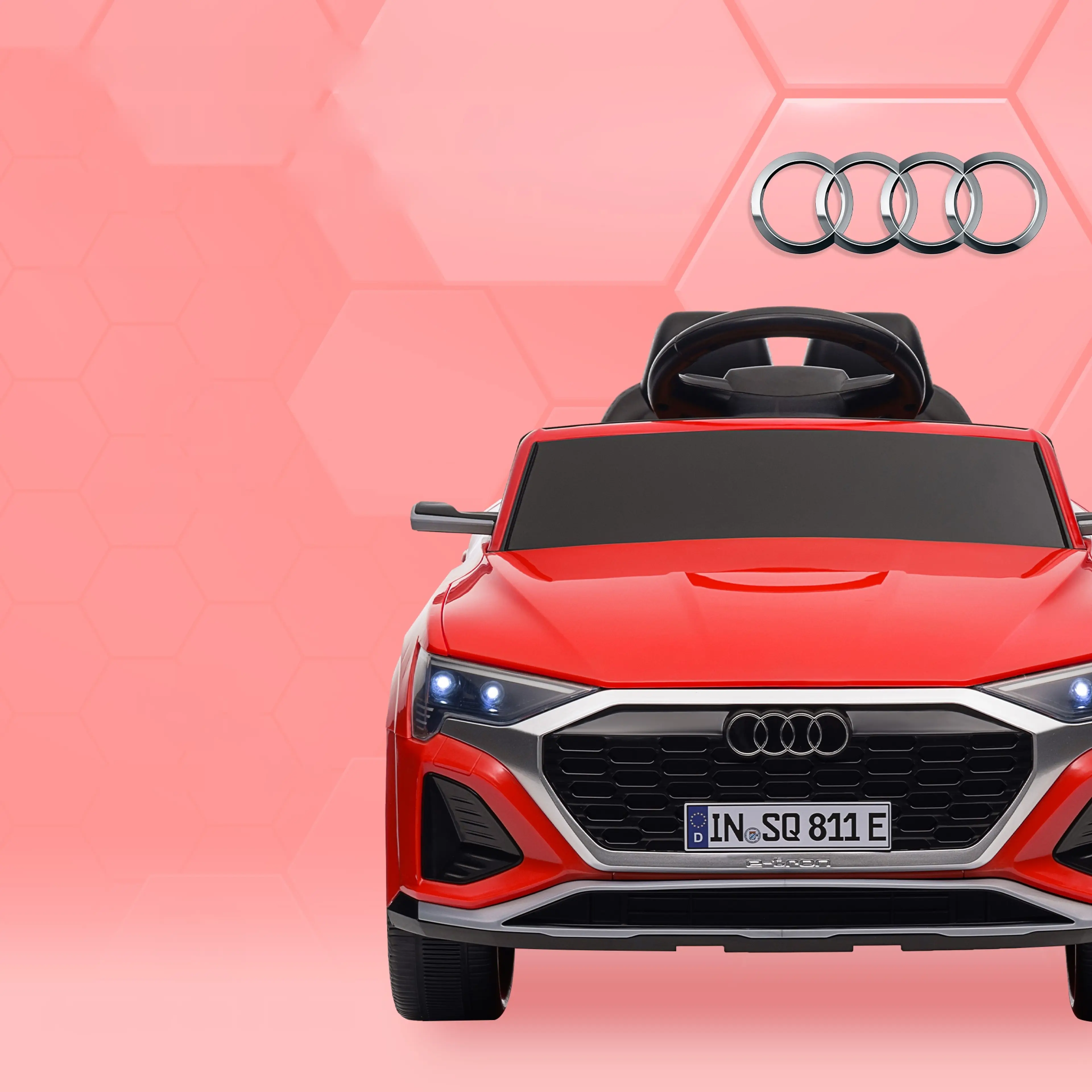 Röd elbil för barn rakt framifrån med Audi-ringarna i grillen, tända LED-ljus och registreringsskylt