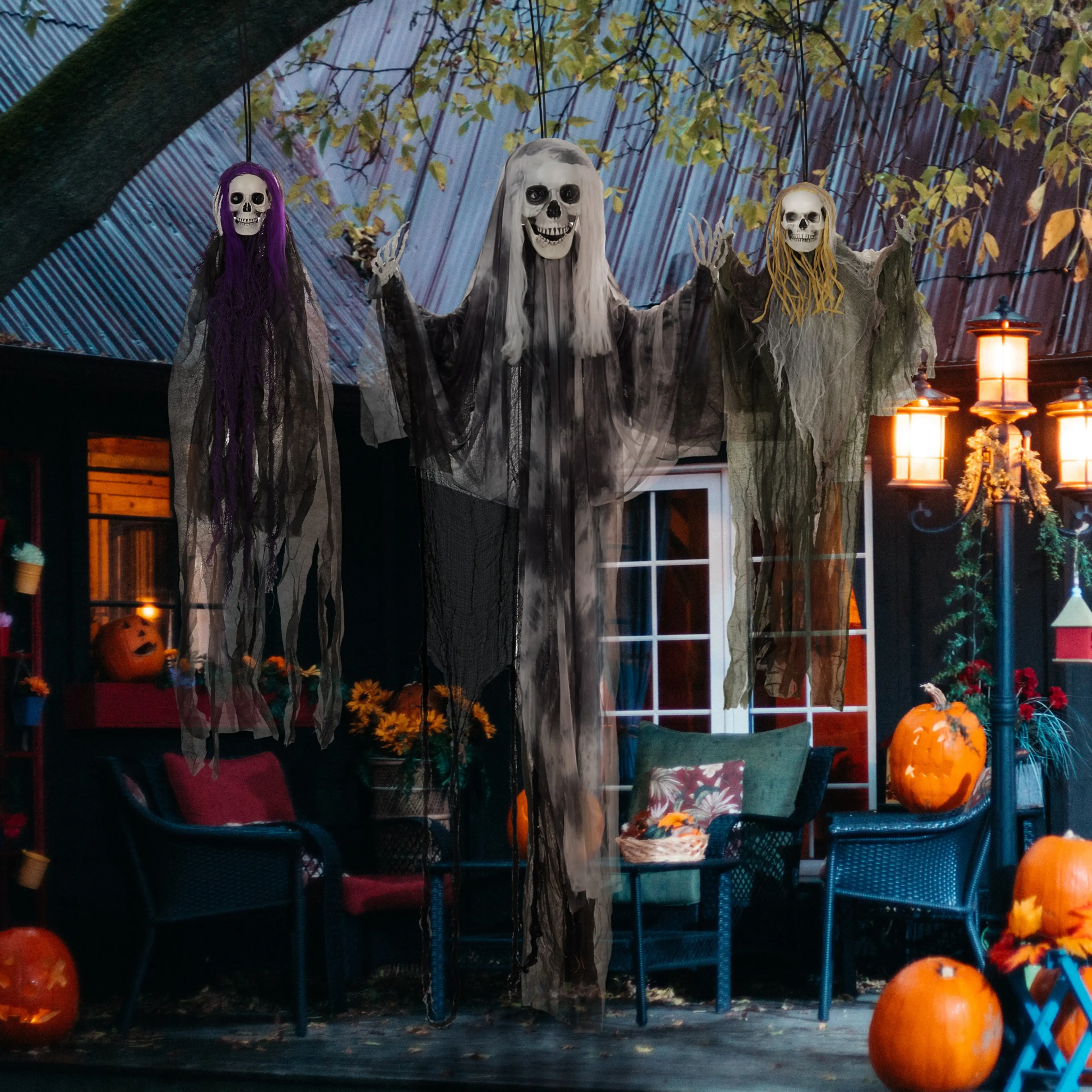 Spökena hänger under taket på en veranda med pumpor och tända lyktor