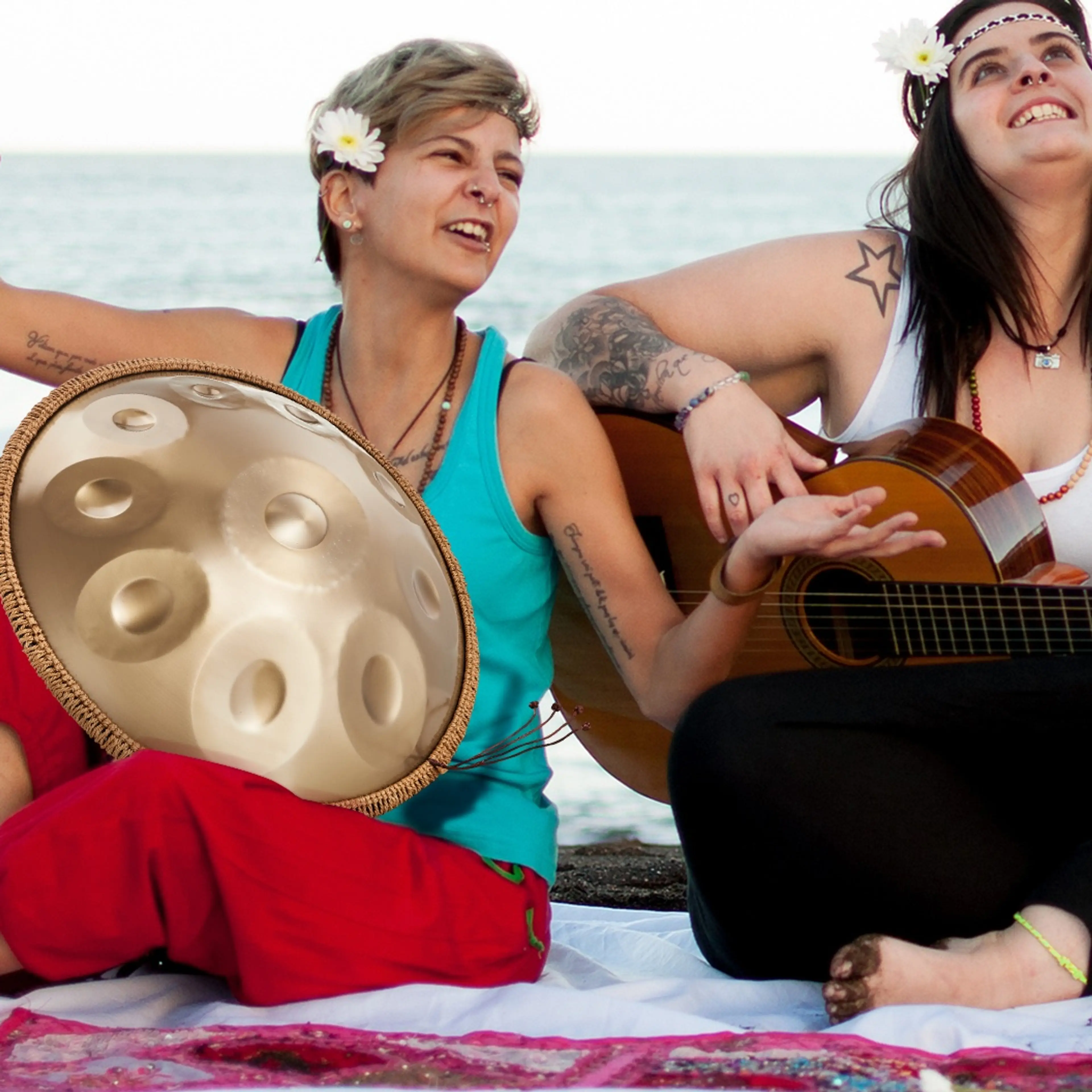 Två personer spelar handpan och gitarr på en strand