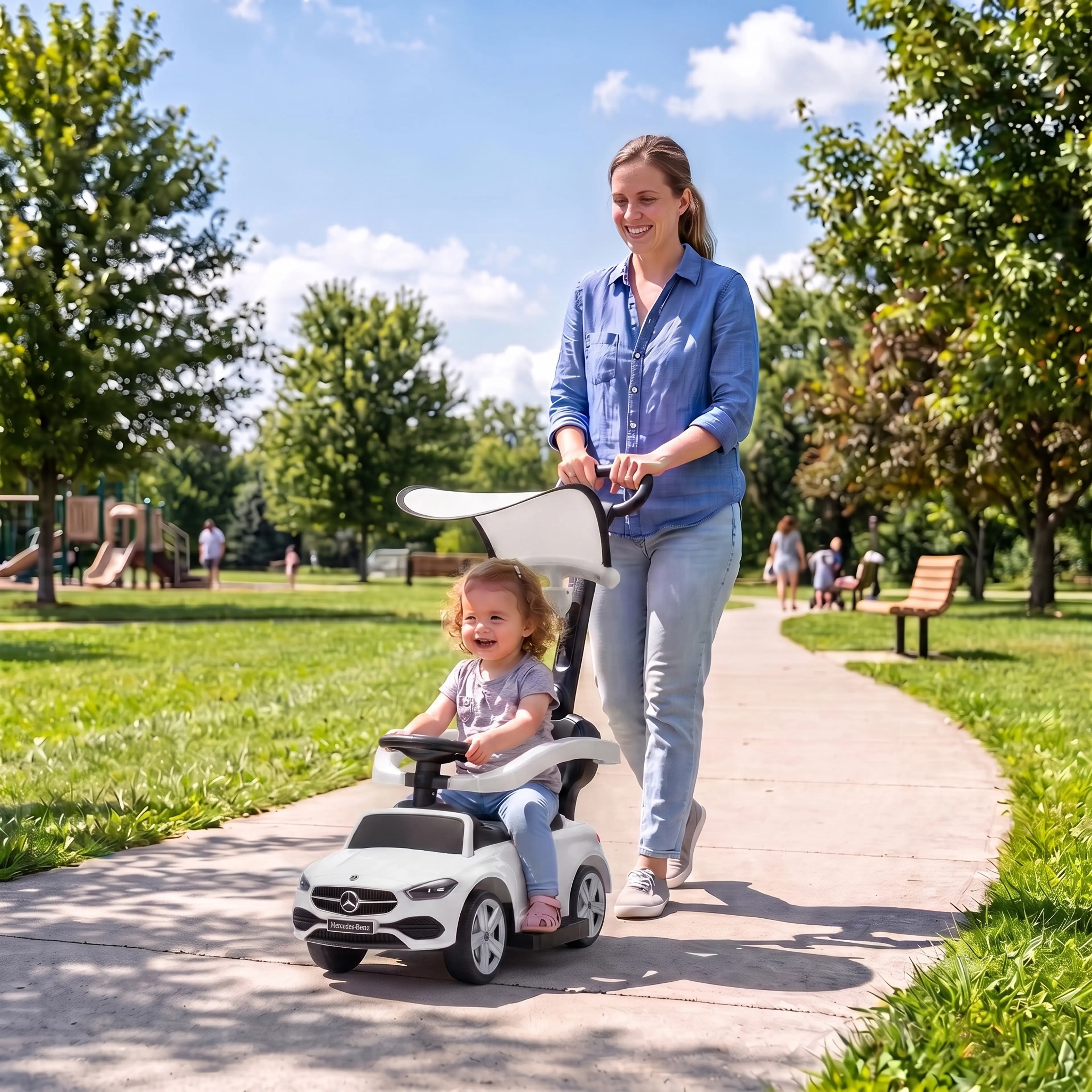 En förälder skjuter ett barn i den vita gåbilen på en gångväg i en park