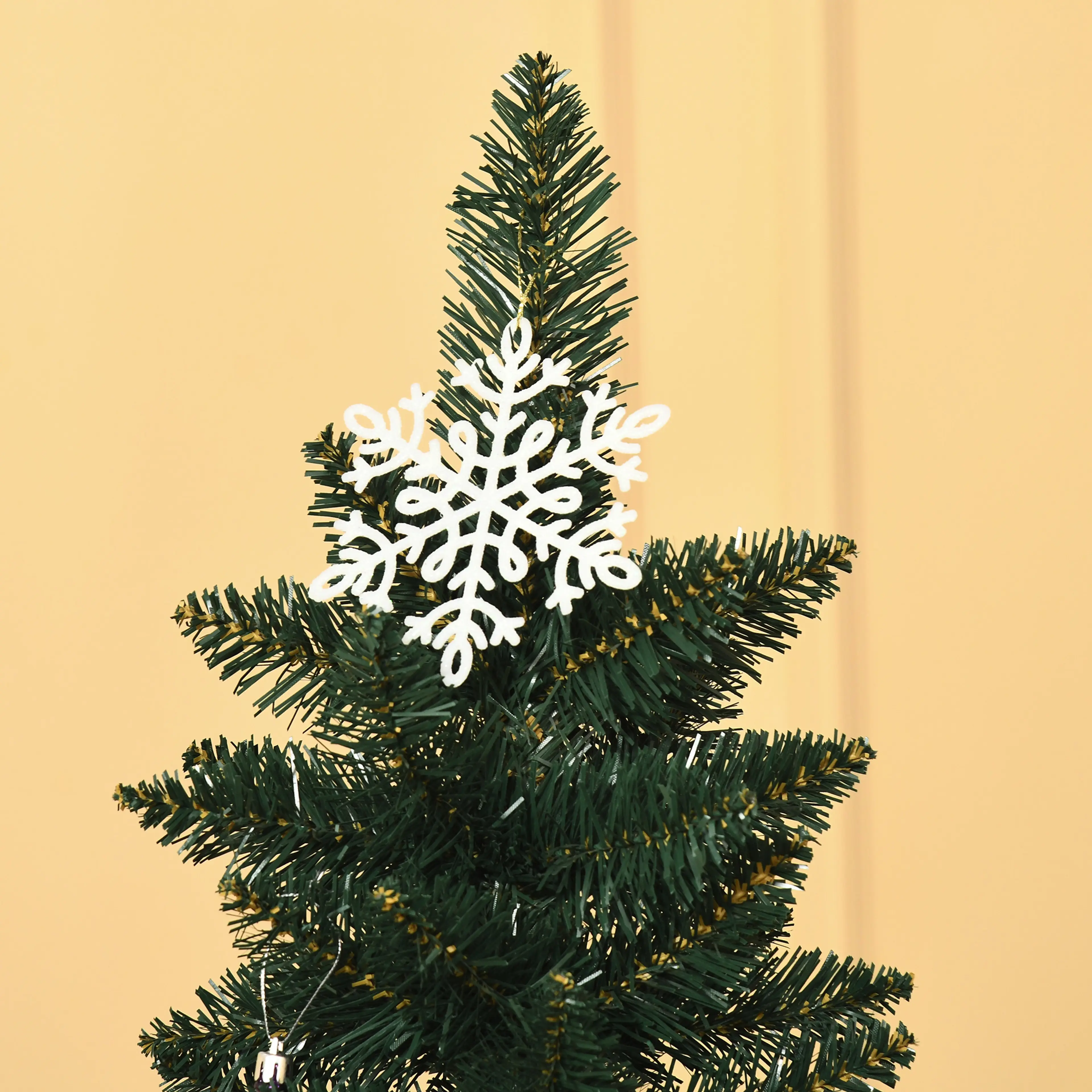 Toppen av granen med en vit snöflinga i plast