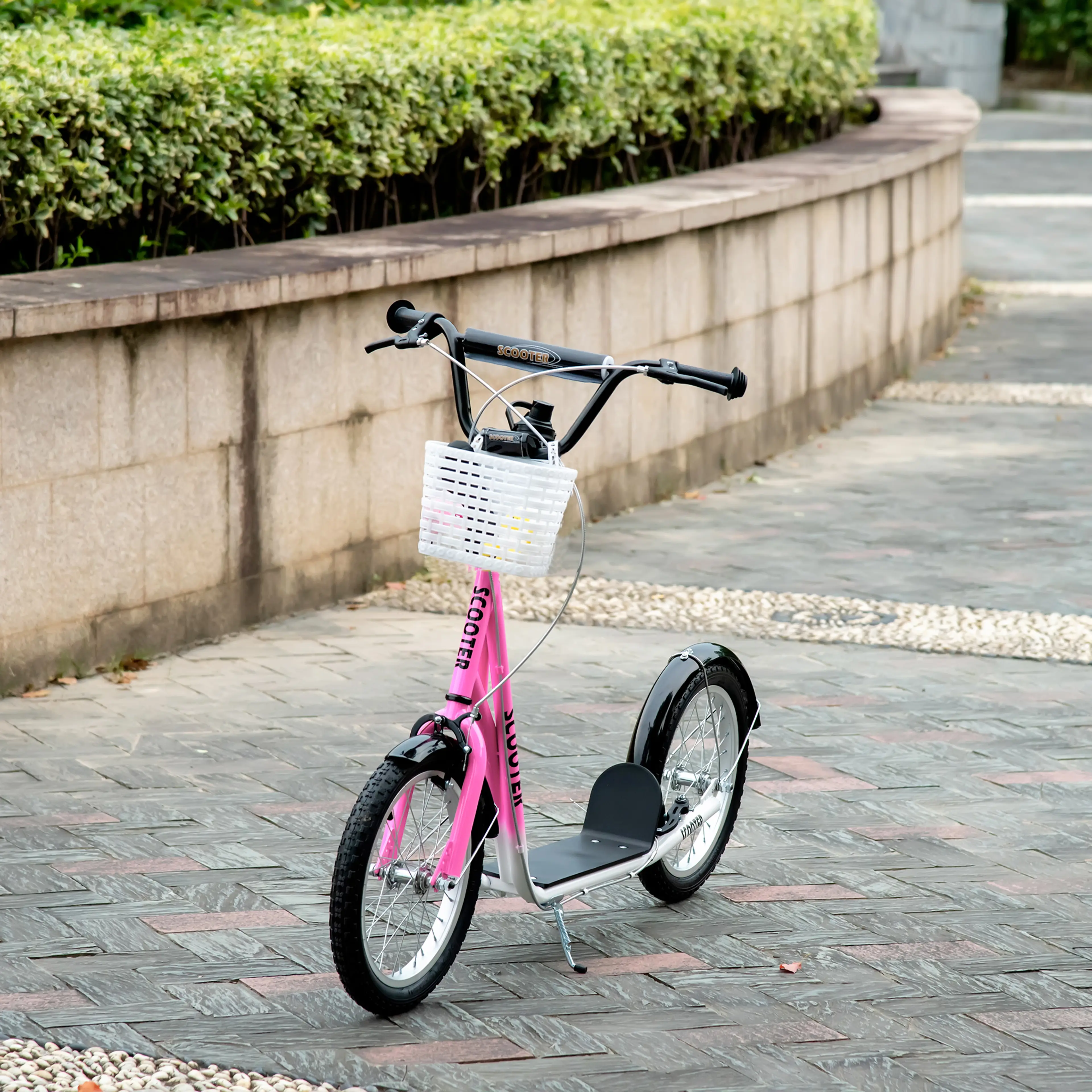 Rosa sparkcykel med vit korg parkerad vid en stenmur