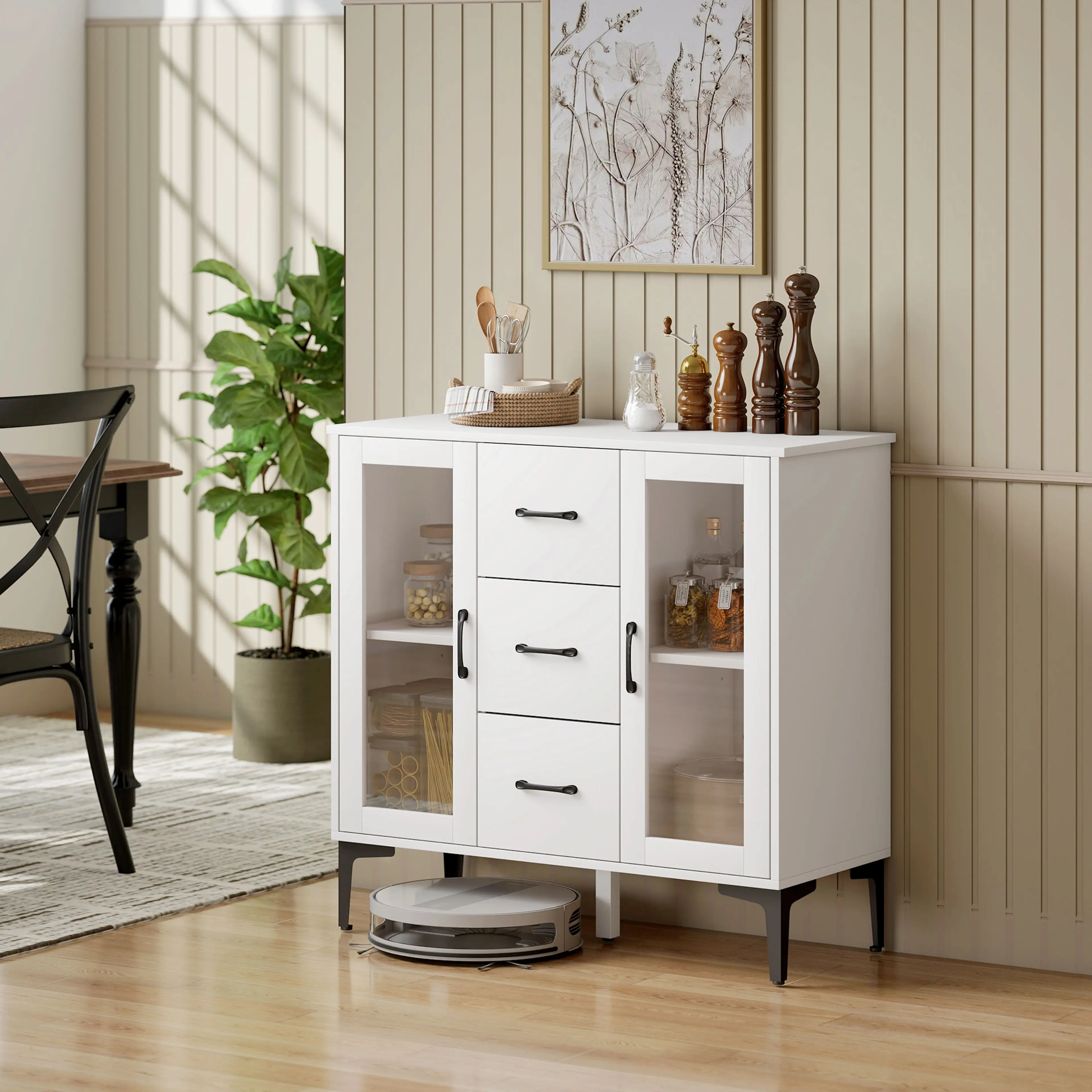 Vitt sideboard med glasdörrar i ett matrum, med kryddkvarnar ovanpå och en robotdammsugare under