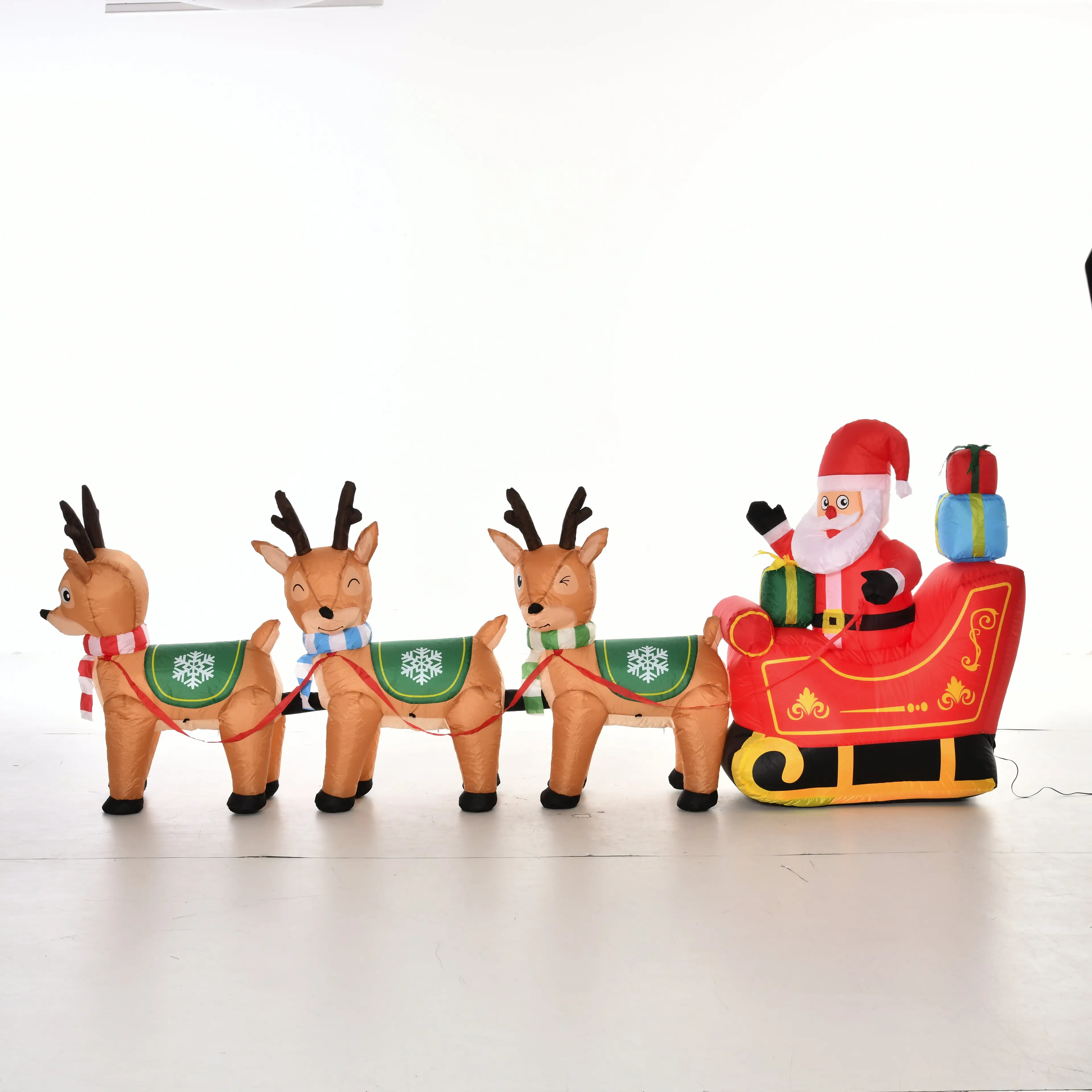 Uppblåsbar tomte i röd släde med julklappar, dragen av tre renar i halsdukar