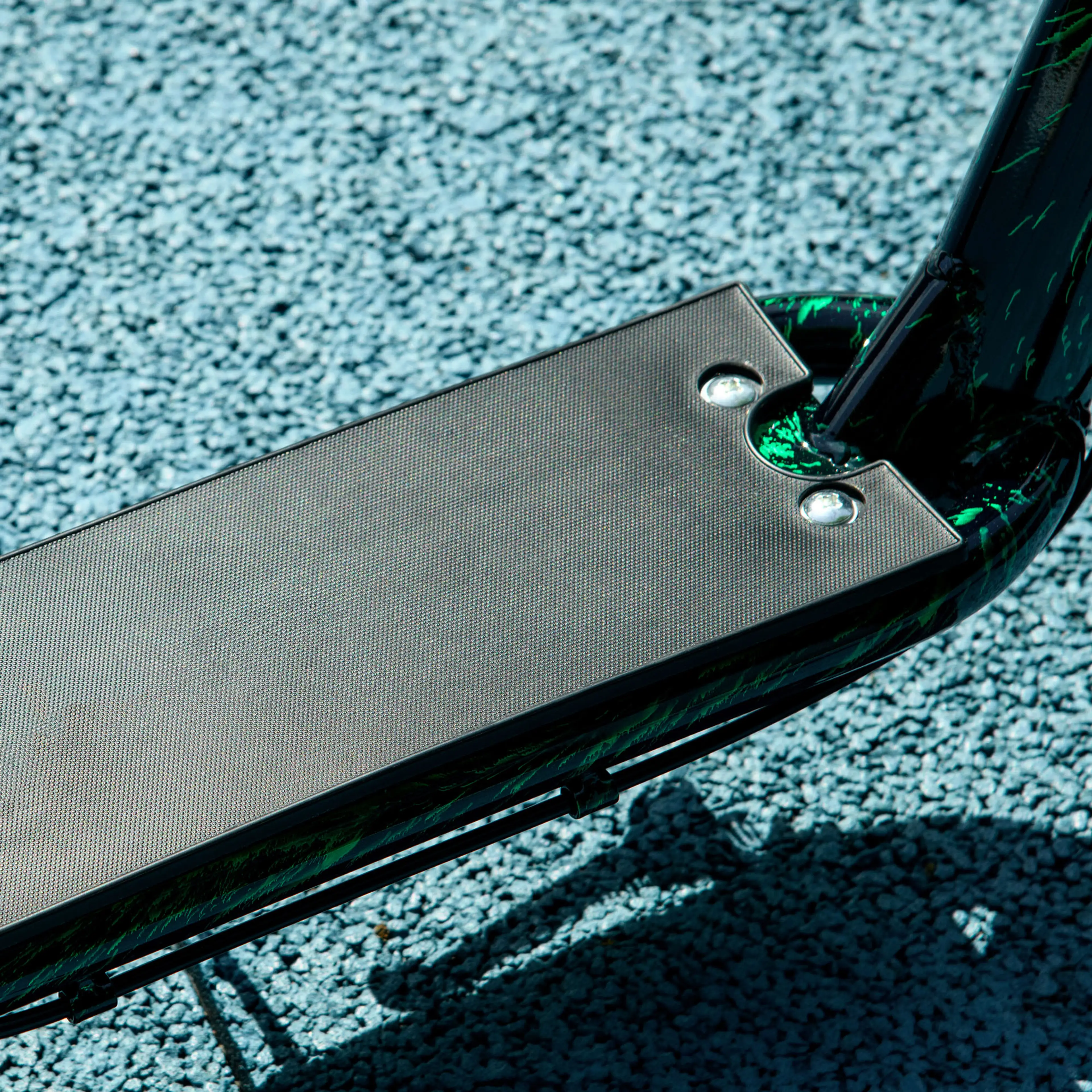 Närbild på den halkfria fotplattan på grön sparkcykel