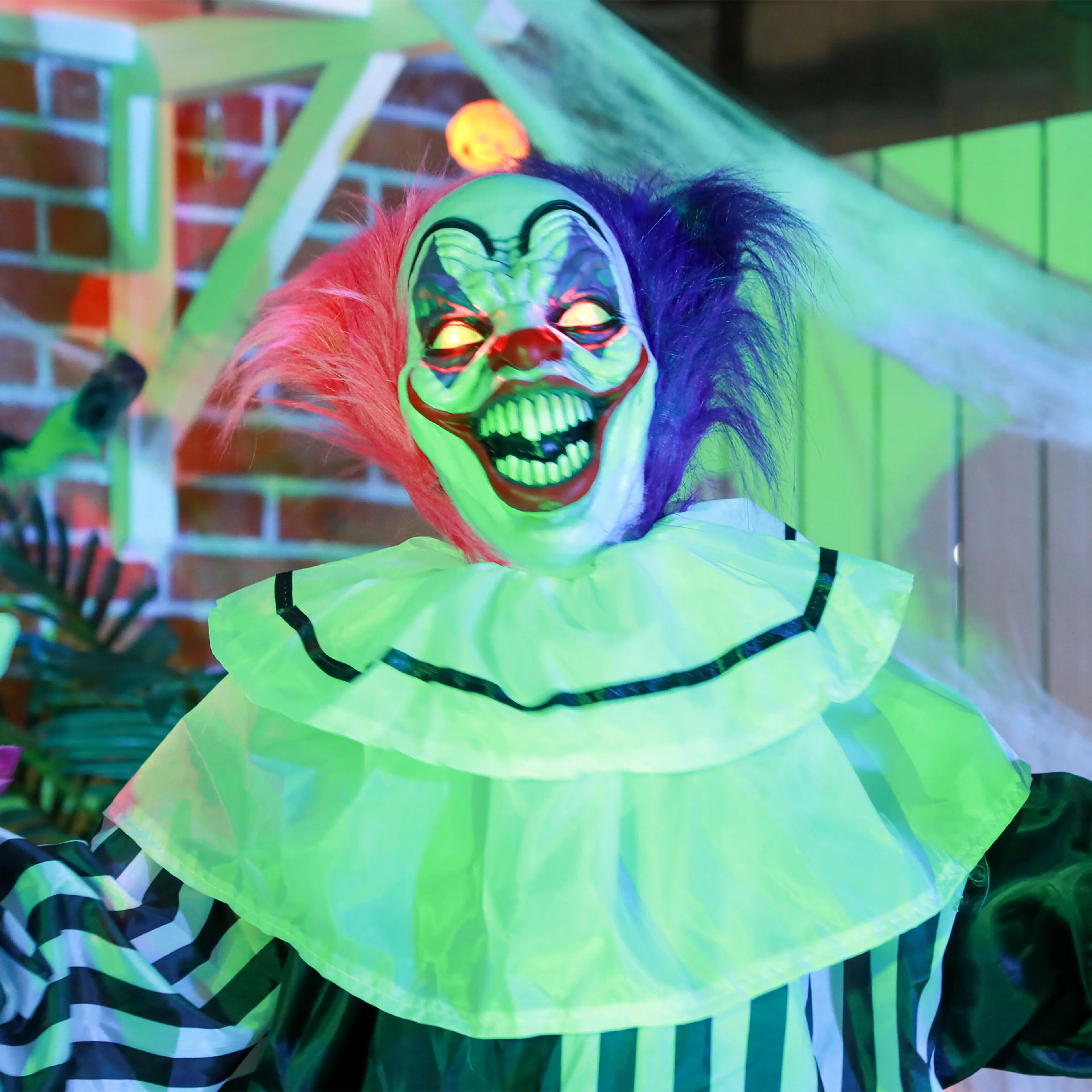 Clownen upplyst vid en tegelvägg med spindelnät