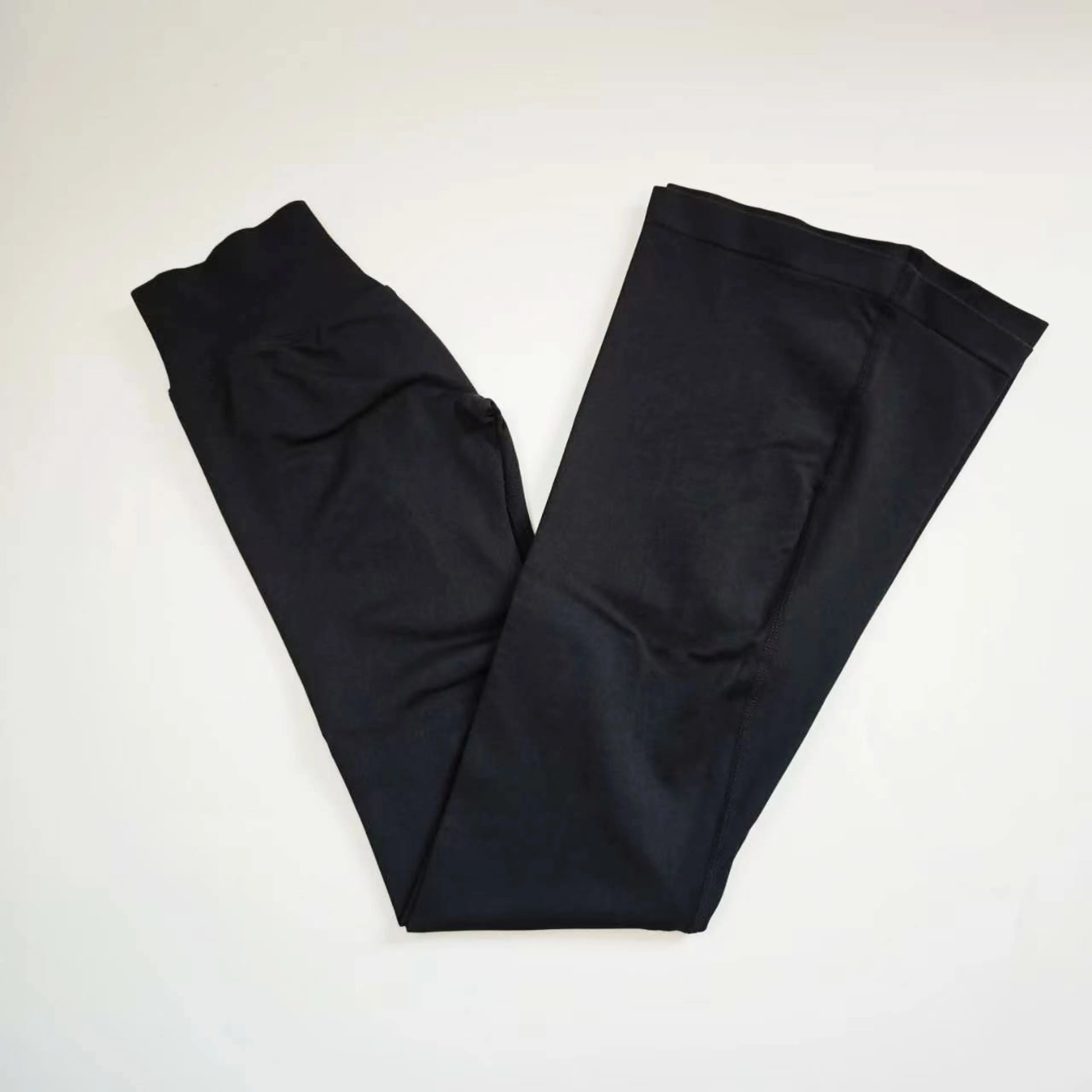 Svarta utsvängda leggings utlagda platt, benen vidgar sig nedanför knät