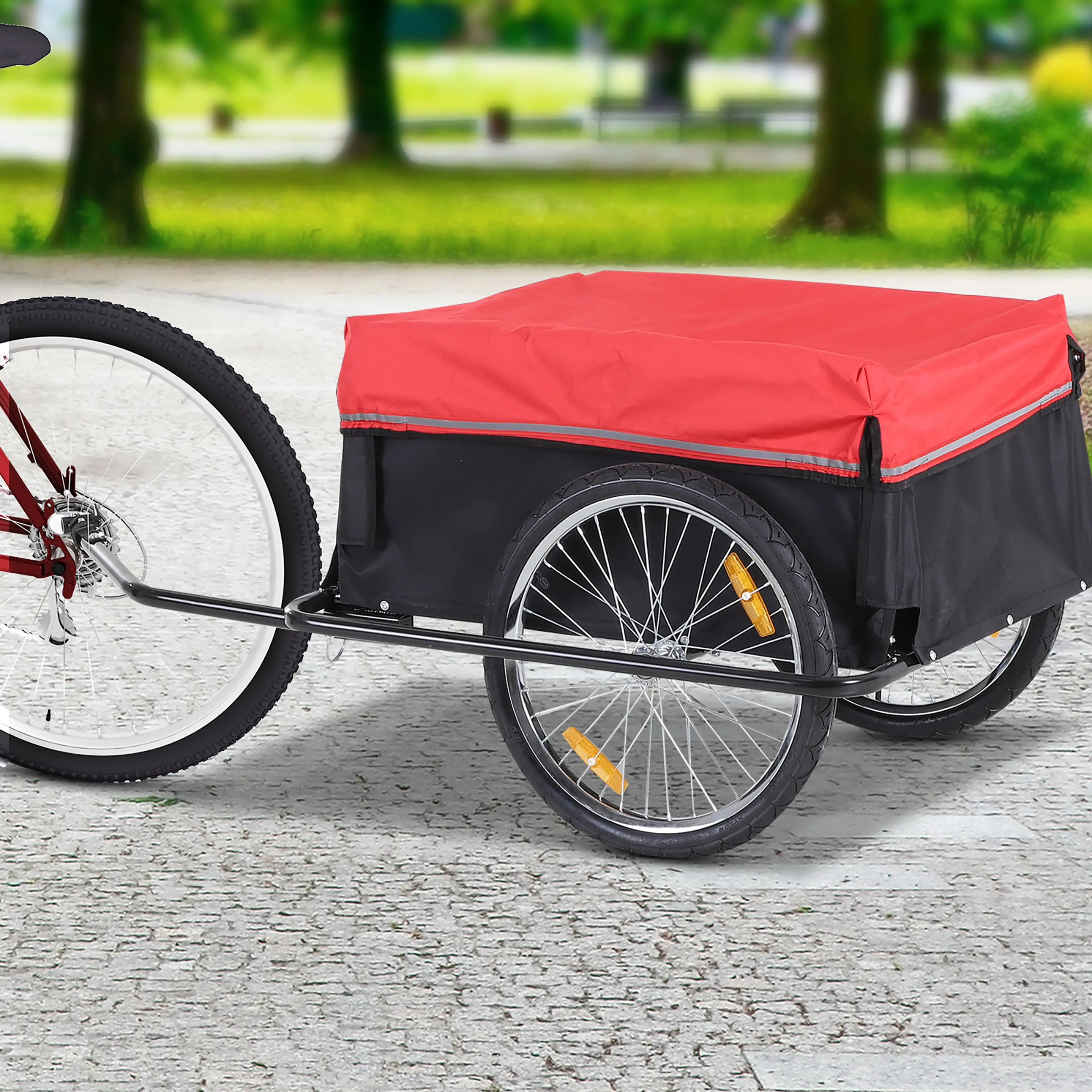 Cykelkärran kopplad bakom en röd cykel på en stenlagd gång i en park