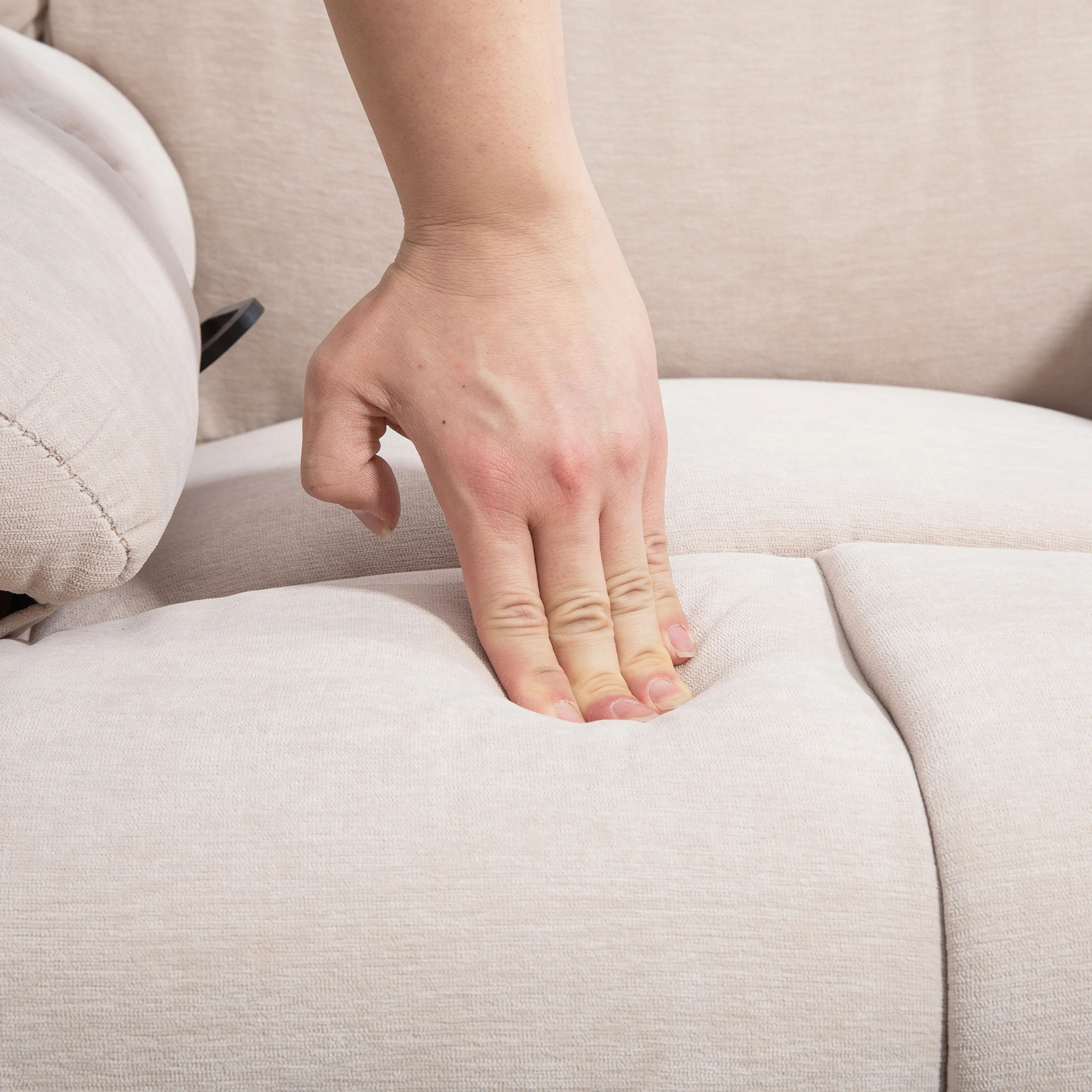 Närbild där en hand trycker ner i sitsens stoppning