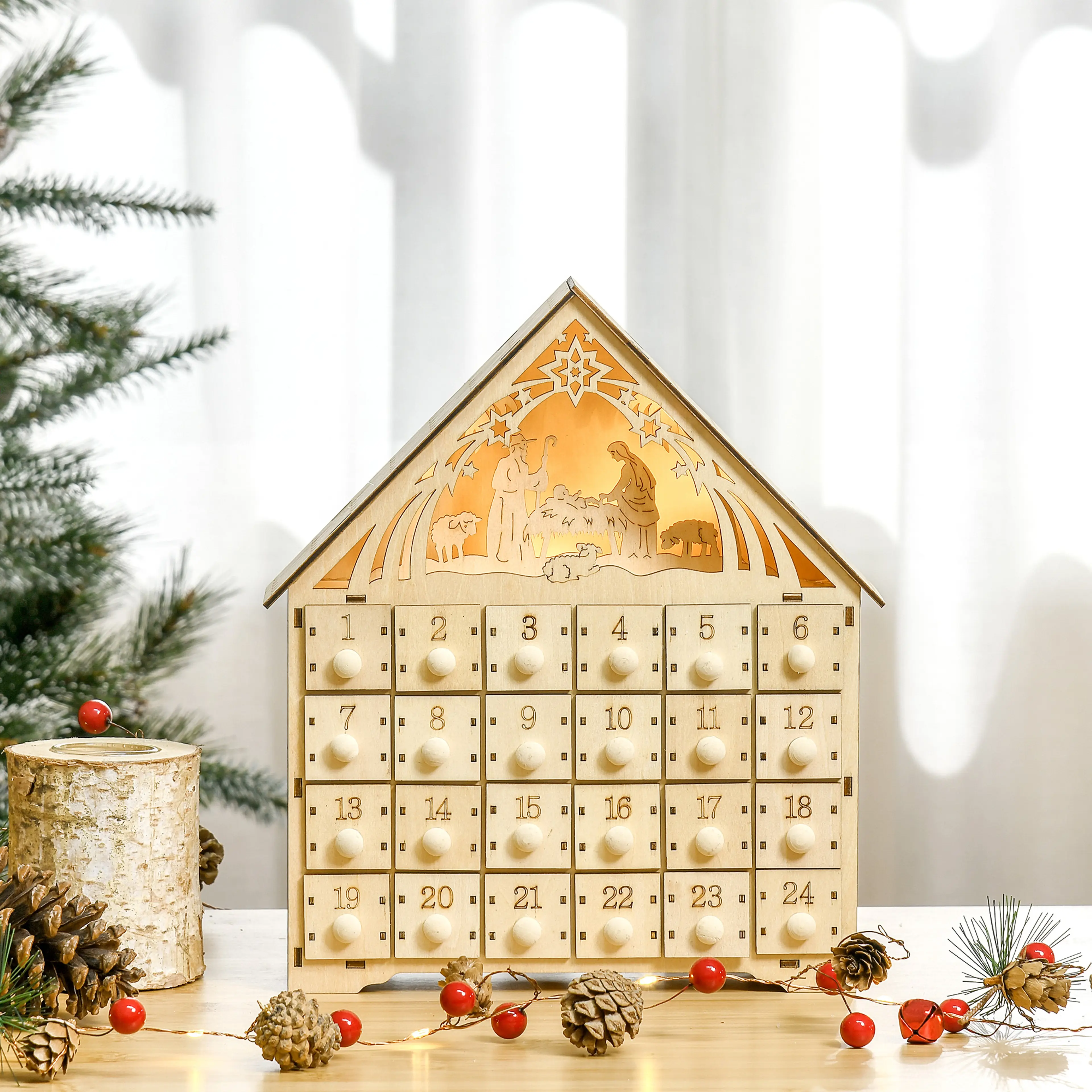 Adventskalendern bredvid en björkstam, kottar och en grankvist