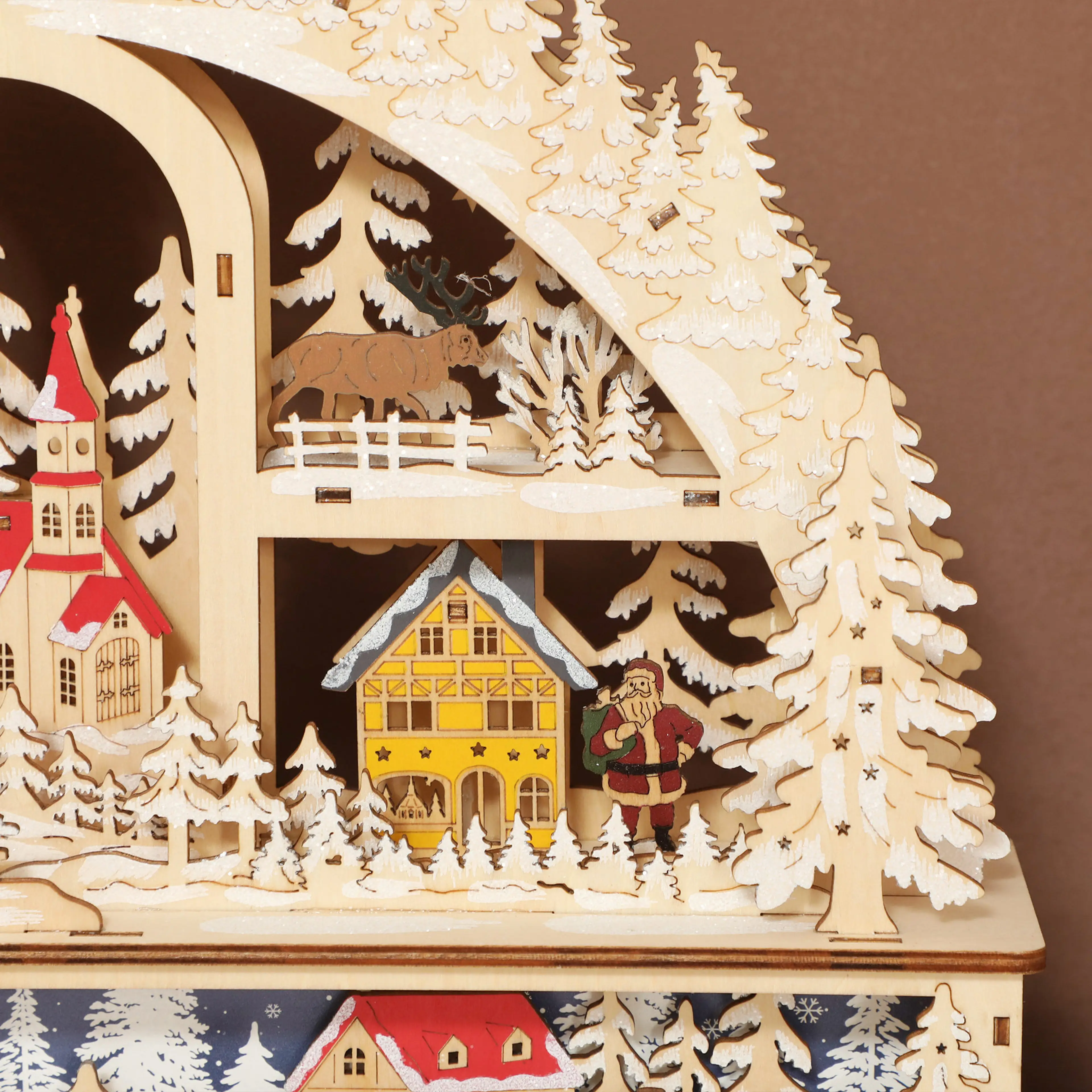 Närbild på julbyns hus, kyrka, granar och tomte i trä