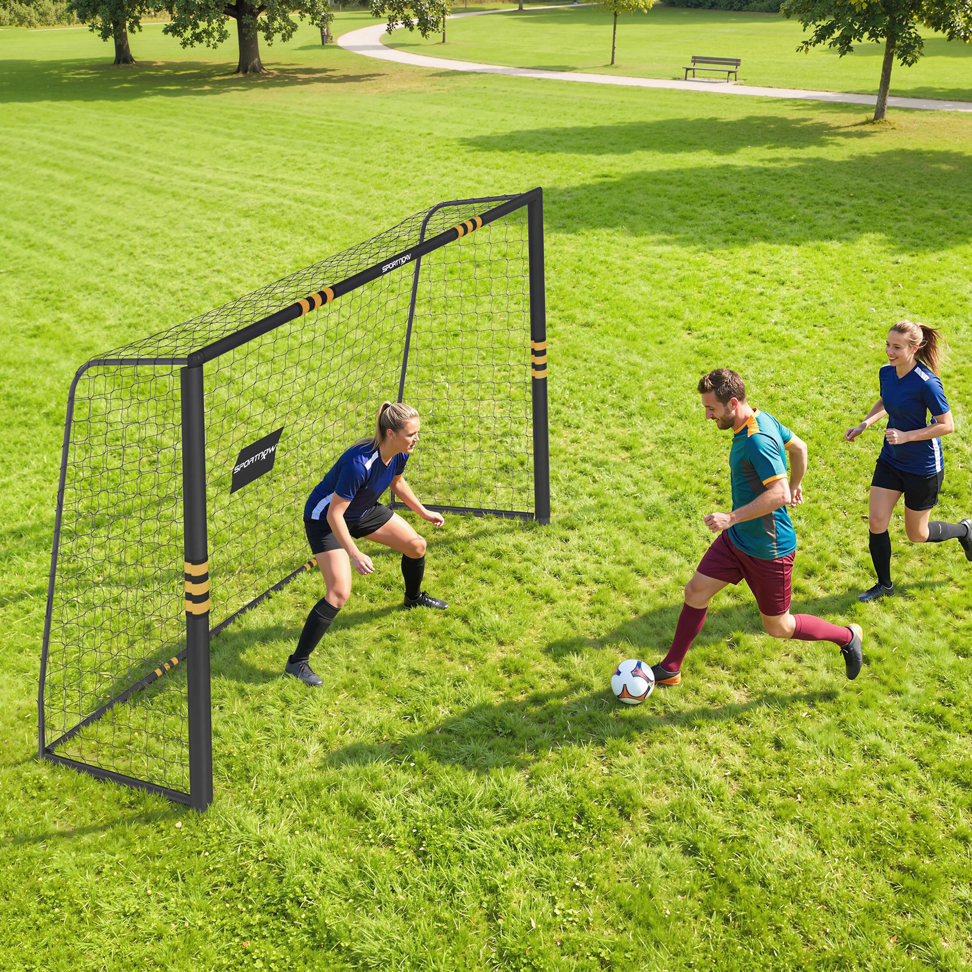 Familj spelar fotboll mot målet i en park