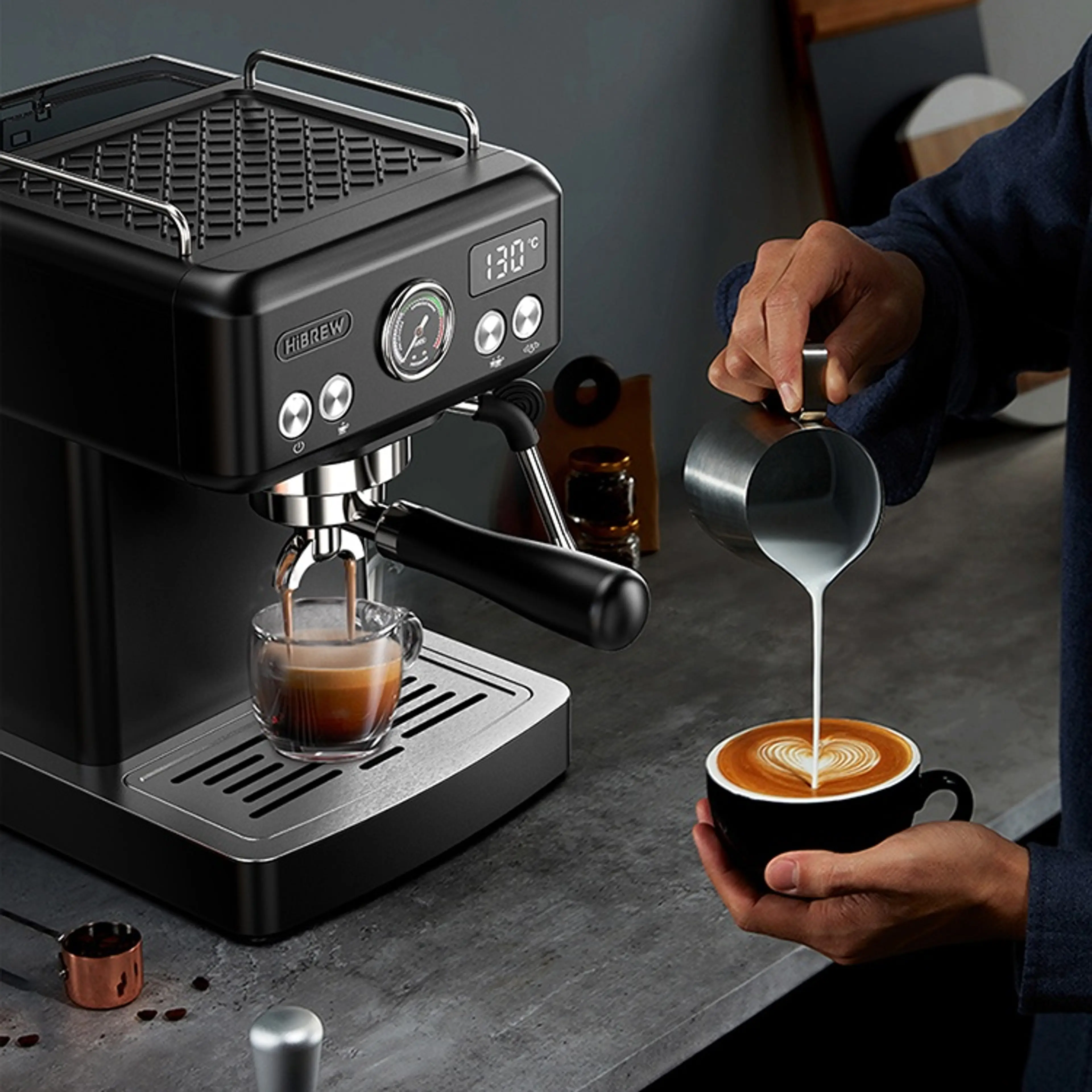 Mjölk hälls till latte art i en kopp bredvid espressomaskinen med ångröret nedfällt