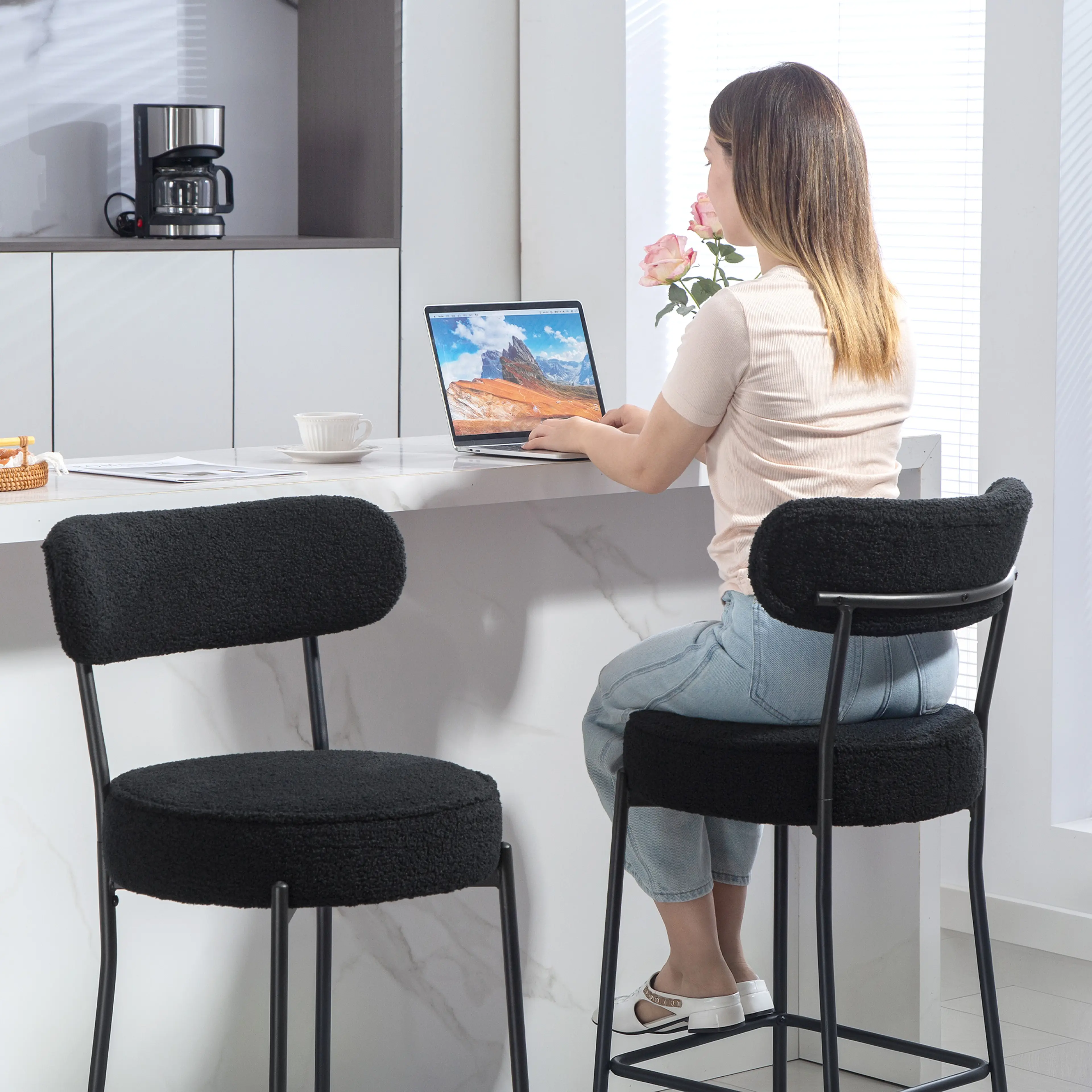 Kvinna arbetar vid en bärbar dator på en svart barstol med rund sits