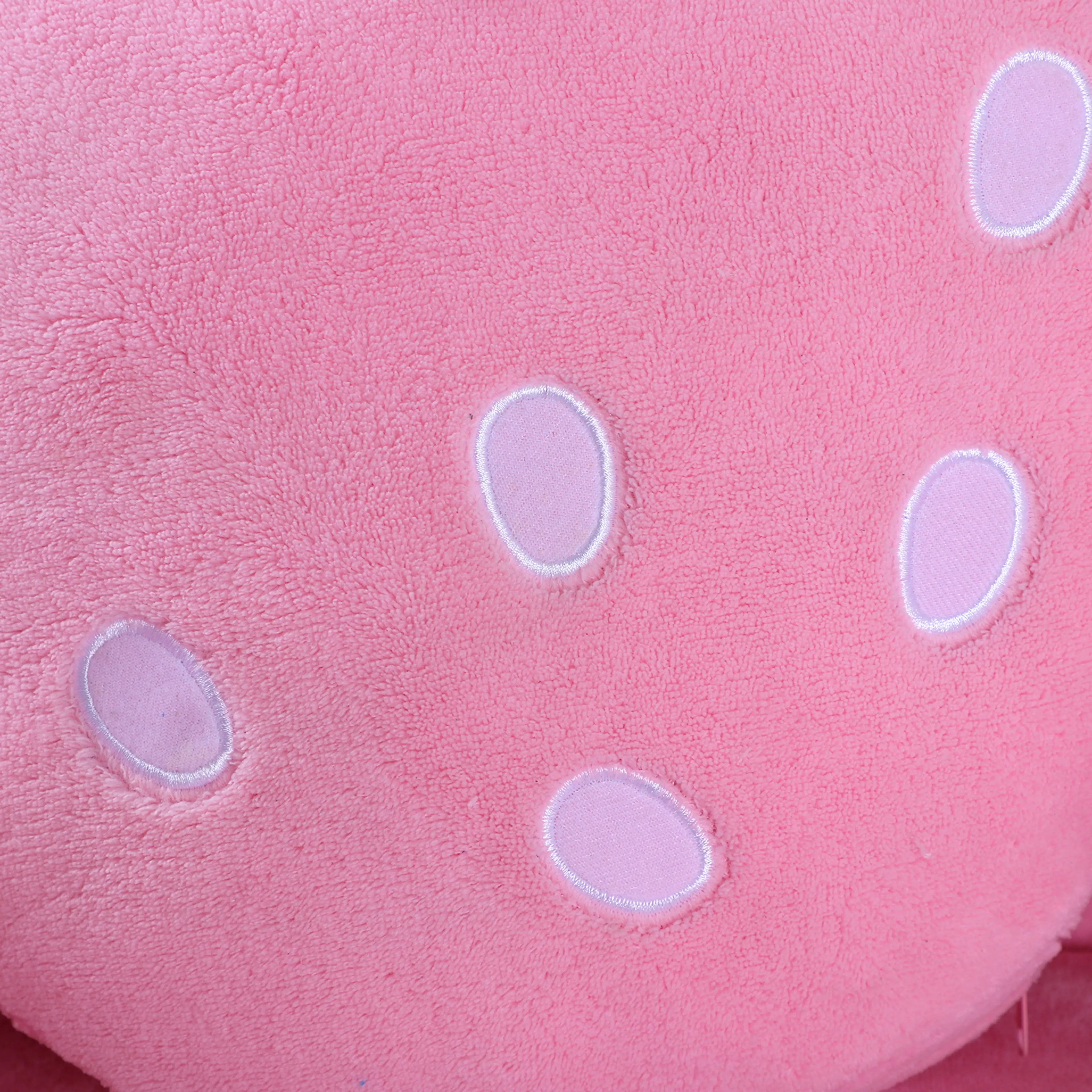 Närbild på jordgubbskuddens rosa yta med vita prickar