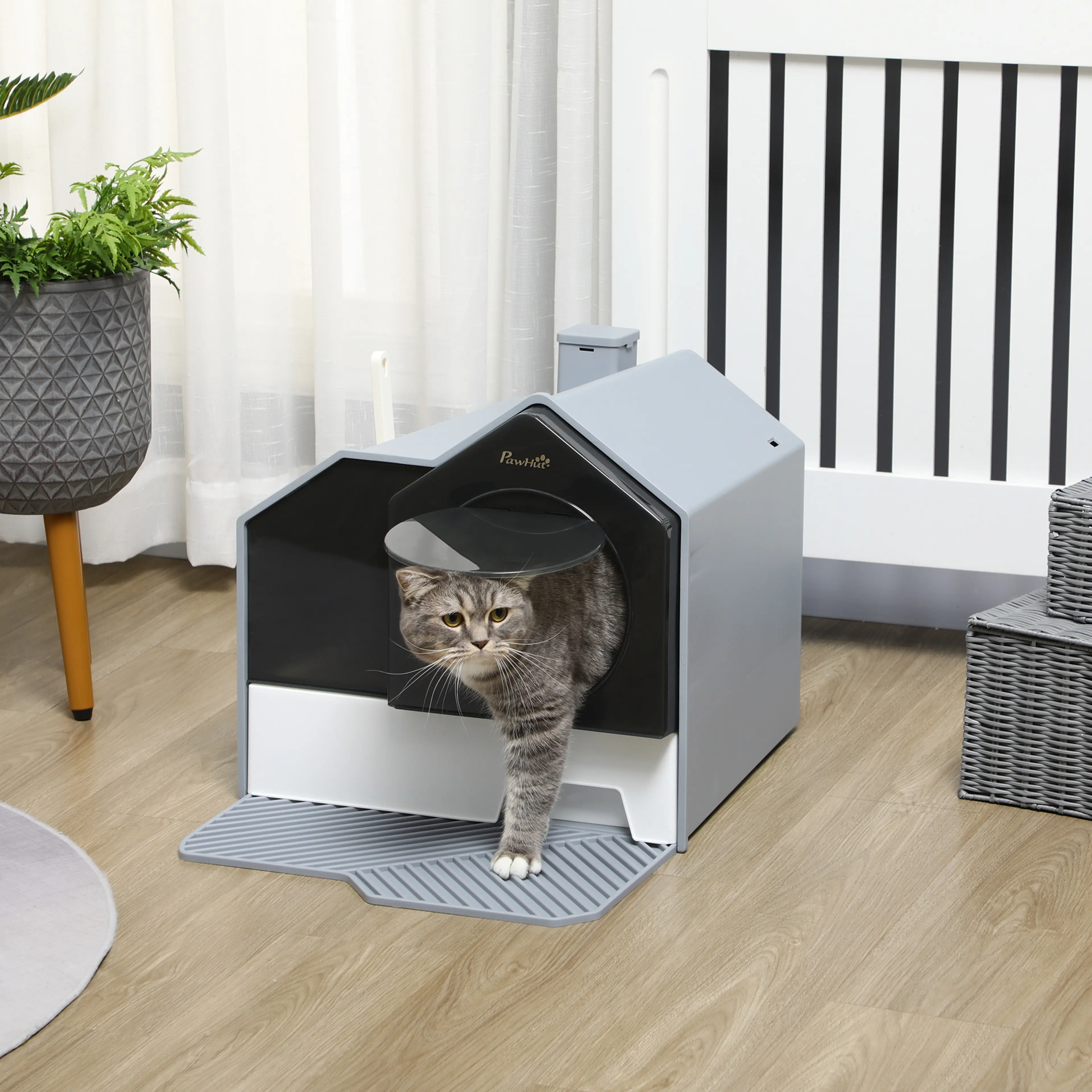 Kattlådan på ett trägolv med en katt som kliver ut genom luckan