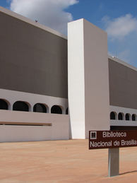 Fachada moderna da Biblioteca Nacional de Brasília, onde acontecerá o Encontro de Literatura Fantástica no dia 22 de agosto de 2026, sob céu azul, com placa marrom em primeiro plano.