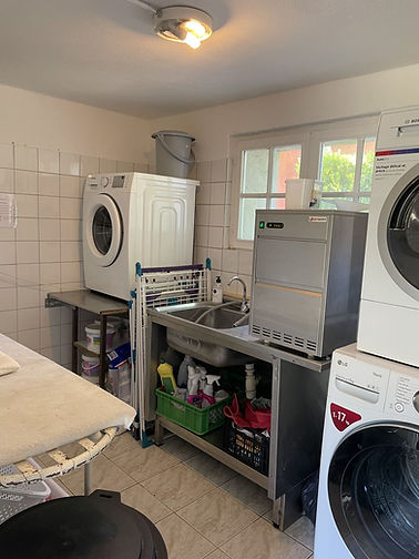 Professional laundry room equipped with LG and Bosch appliances, commercial stainless steel utility sink, and ice maker for event service.