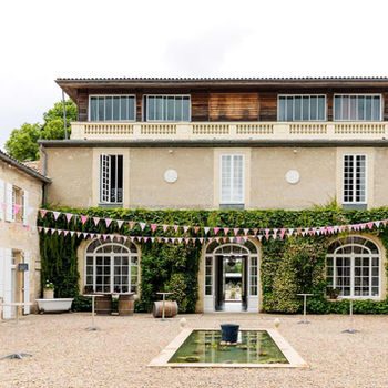 Courtyard of Château Destinée decorated with bunting for a celebration, featuring ivy-clad walls, arched windows, and a central water feature.