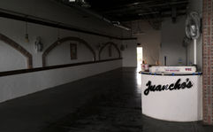  A restaurant interior under renovation, featuring brick archways, wall sconces, and a modern bar counter.
