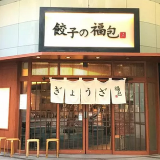 餃子の福包　新宿店」。外はサクサク、中はジューシーな薄皮の焼餃子は、ニンニクのありなしが選べるのが嬉しい。餃子は大根おろしをトッピングしてさっぱりと頂くのもおすすめ。あんかけ卵ご飯も人気。水餃子にはネギ塩（別オーダー）をトッピングすると美味。
Gyoza Fukubao (Shinjuku location). Crispy on the outside and juicy on the inside, the thin-crust gyoza dumplings are available with or without garlic. We also recommend topping gyoza with grated daikon radish for a refreshing taste. Ankake egg rice is also popular. Boiled dumplings are delicious when topped with green onion salt (separate order).