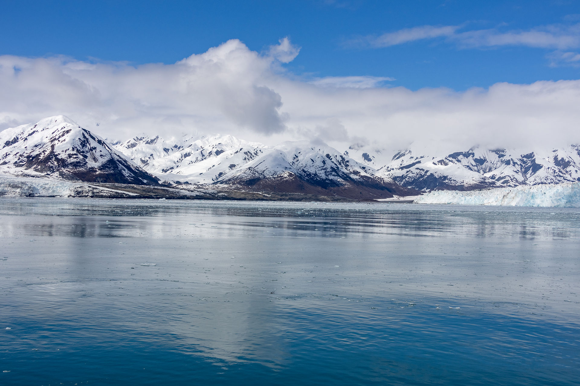 Glass-like water sitting still in front of snow capped mountains