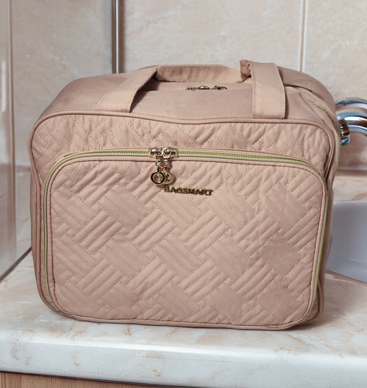 Blush pink cosemetic bag fully zipped up sitting on a counter