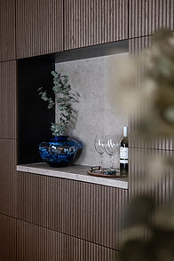 Whistler duplex custom bar with dark wood slat wall, stone niche, blue vase, glassware, wine bottle, and warm residential design details.