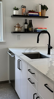Vancouver kitchen renovation with white cabinetry, black faucet, marble-look countertop, open shelving, and styled kitchen details.